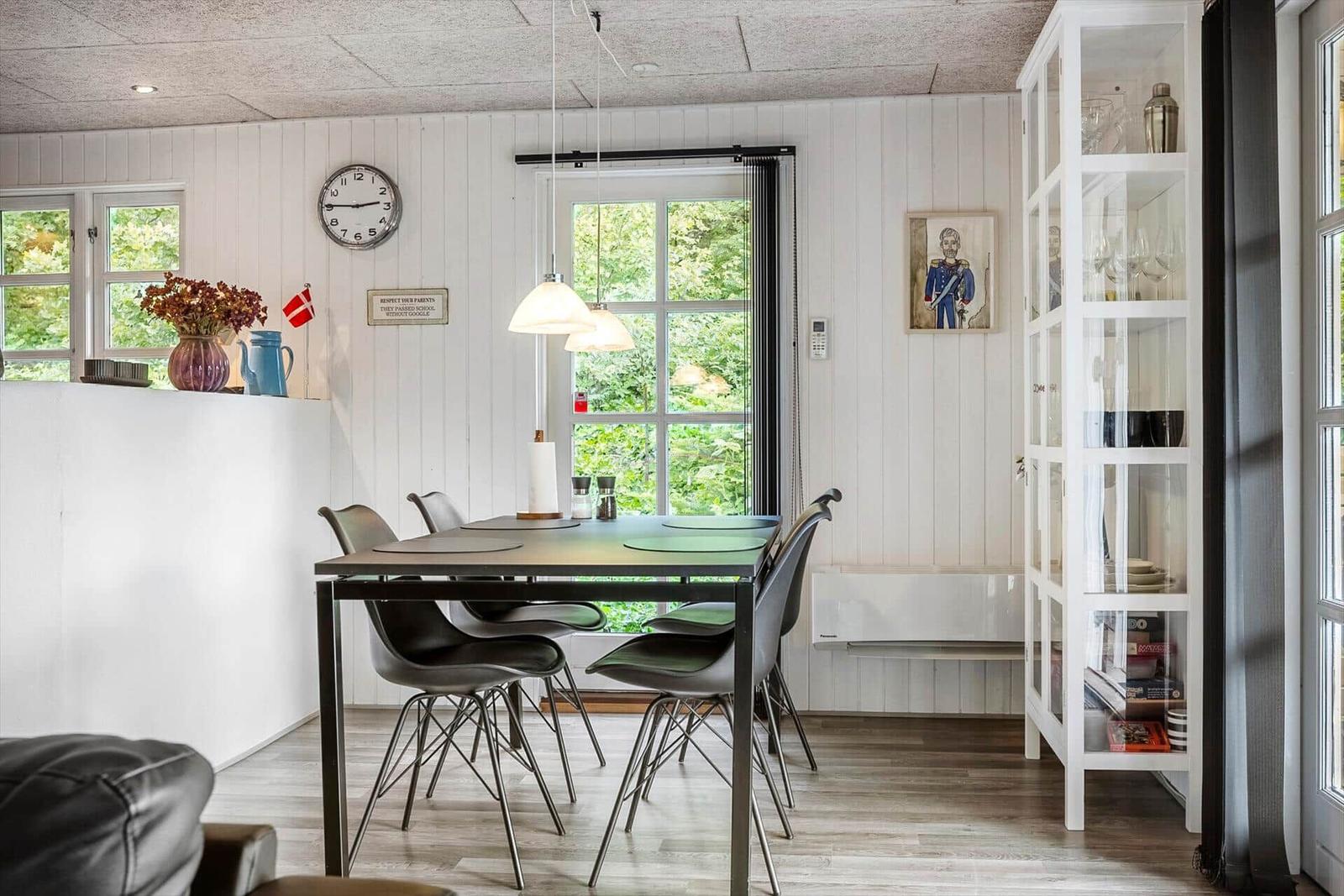 Dining room with table, chairs, and view of green trees.