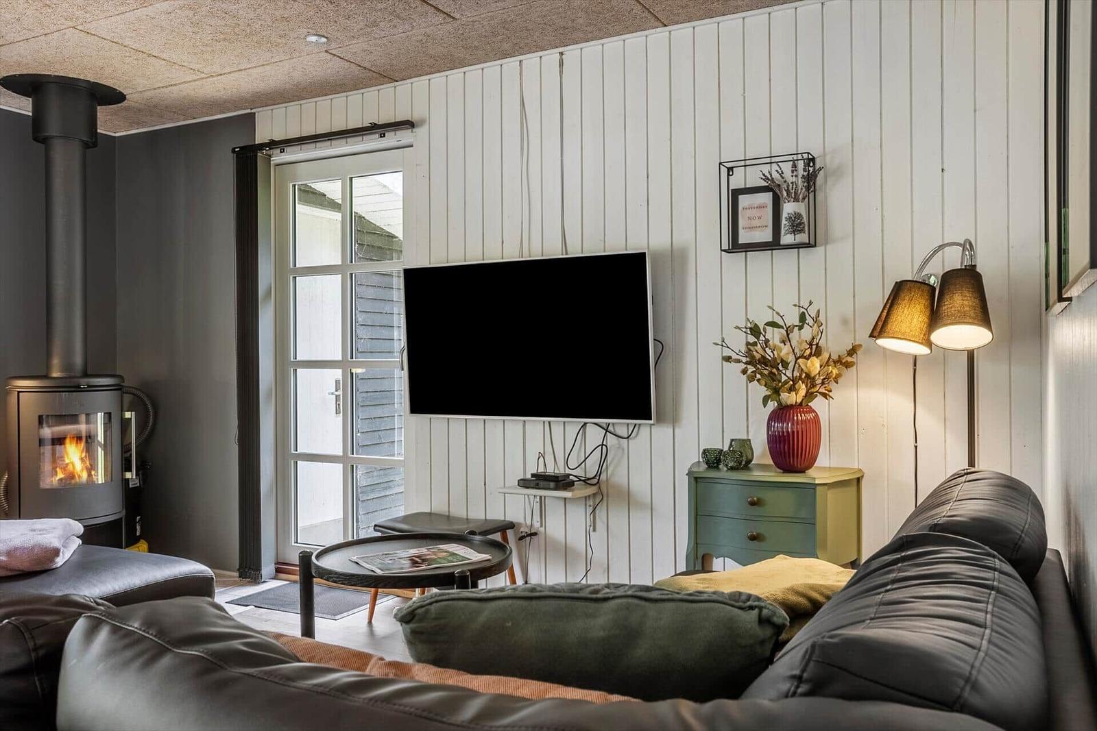 Living room with fireplace, TV, and sofa. Door leads outside.