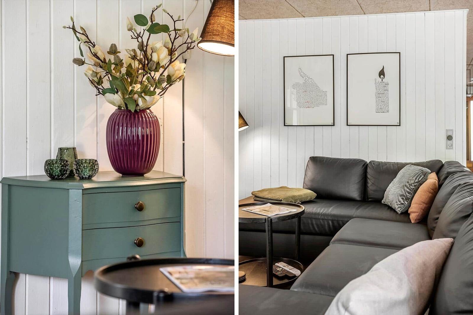 Black leather sofa with cushions, wall art, and wooden furniture with vase.