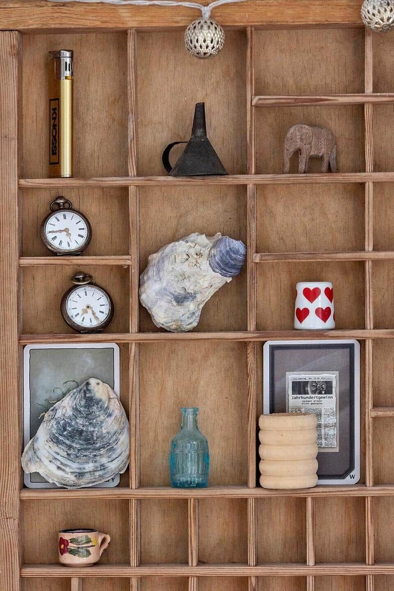 Holzregal mit verschiedenen Gegenständen wie Uhren, Muscheln und Keramik.