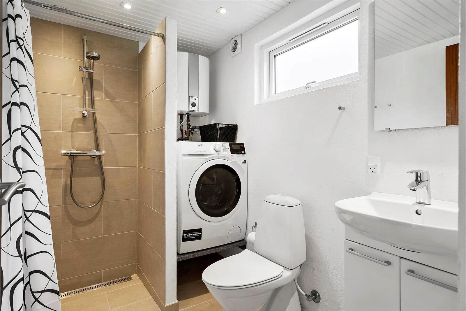 Badezimmer mit Dusche, Waschmaschine, WC und Waschbecken.