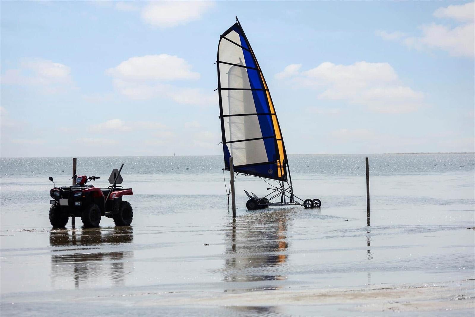 Ein Quad und ein Segelboot stehen im flachen Wasser.
