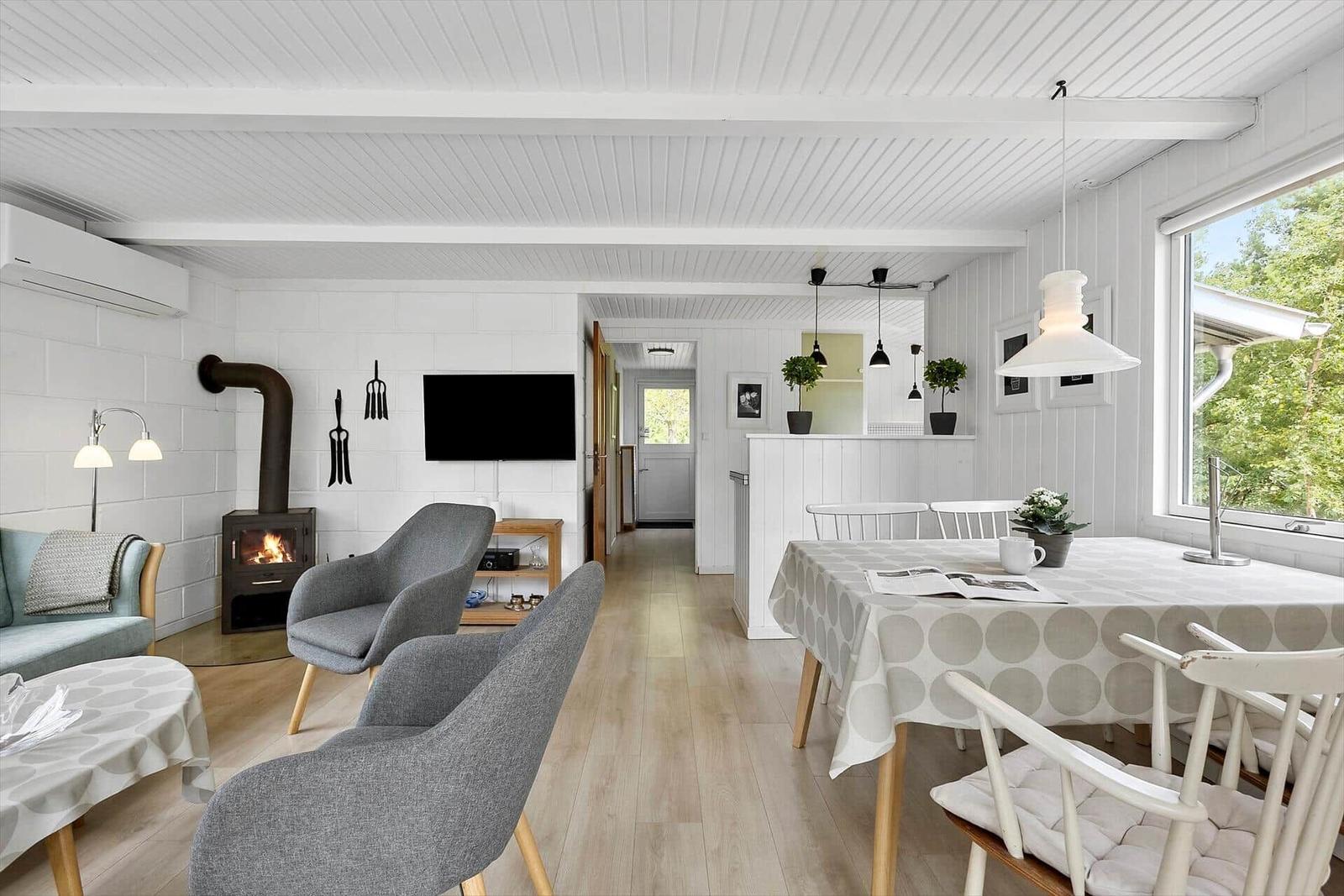 Wohn- und Essbereich mit Kamin, TV und Tisch mit Stühlen.