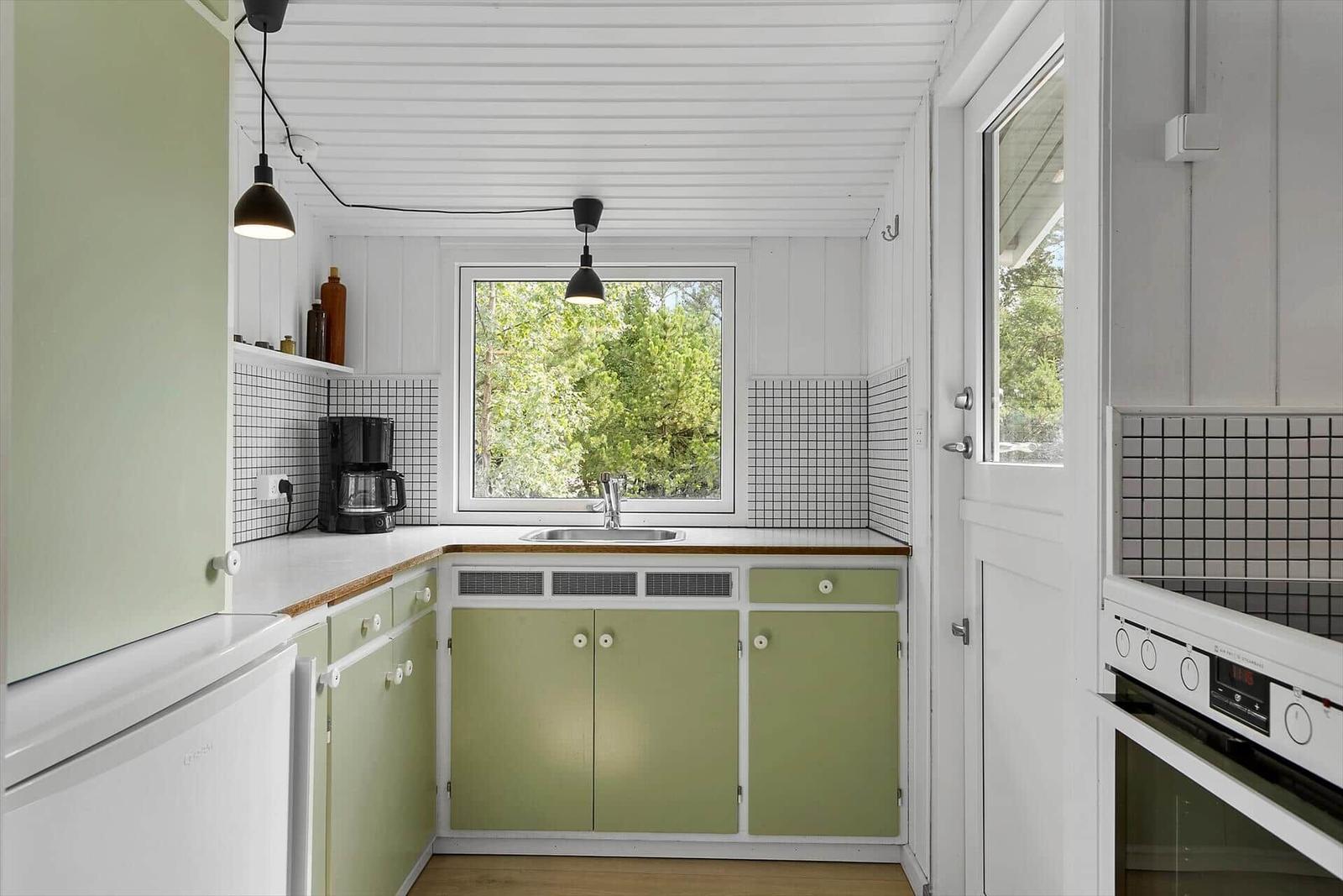 Küche mit grünen Schränken, Fenster und Küchenzeile.