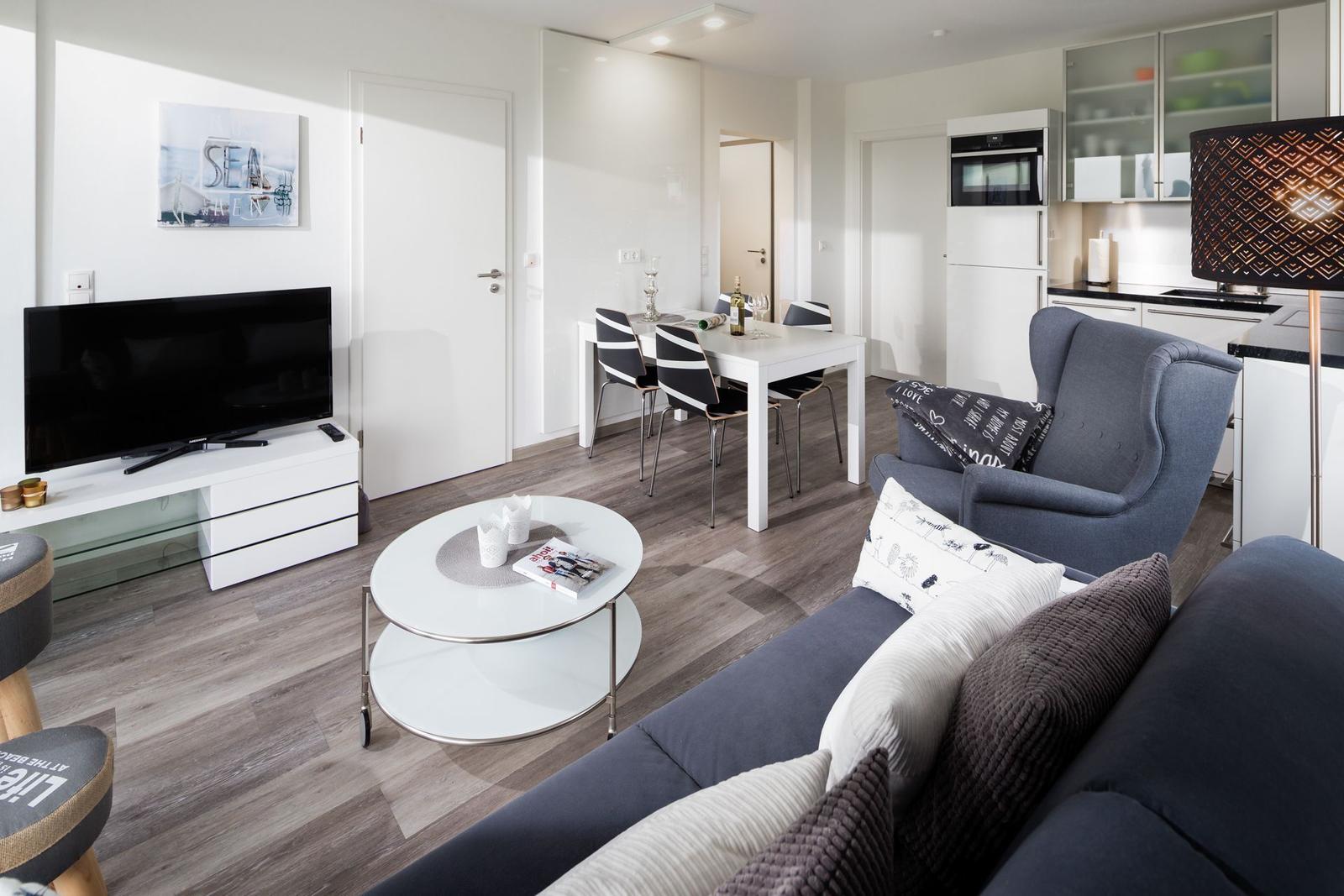 Wohn- und Essbereich mit Sofa, Esstisch und Küchenzeile.