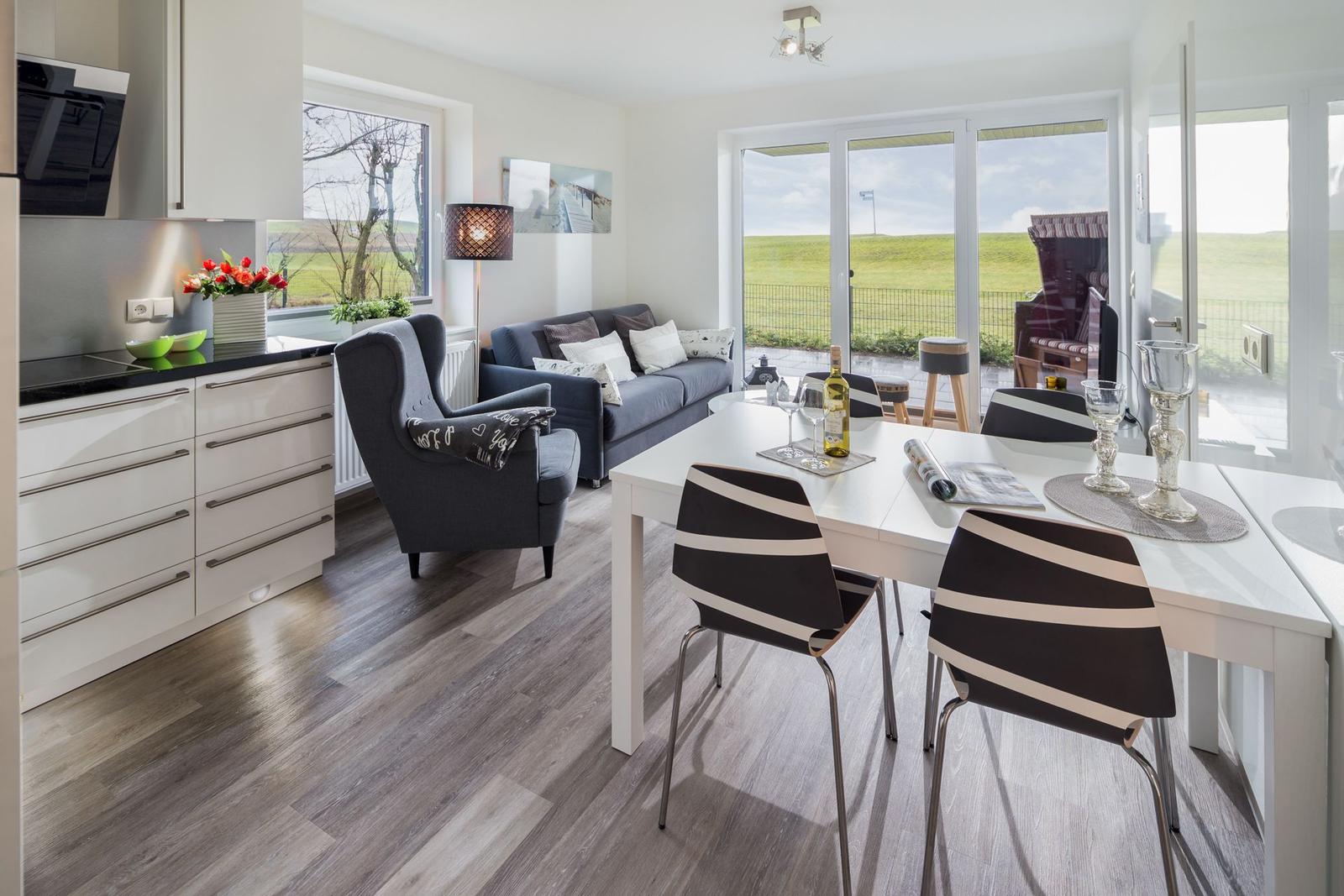 Wohn- und Essbereich mit Küchenzeile und Blick auf grüne Landschaft.
