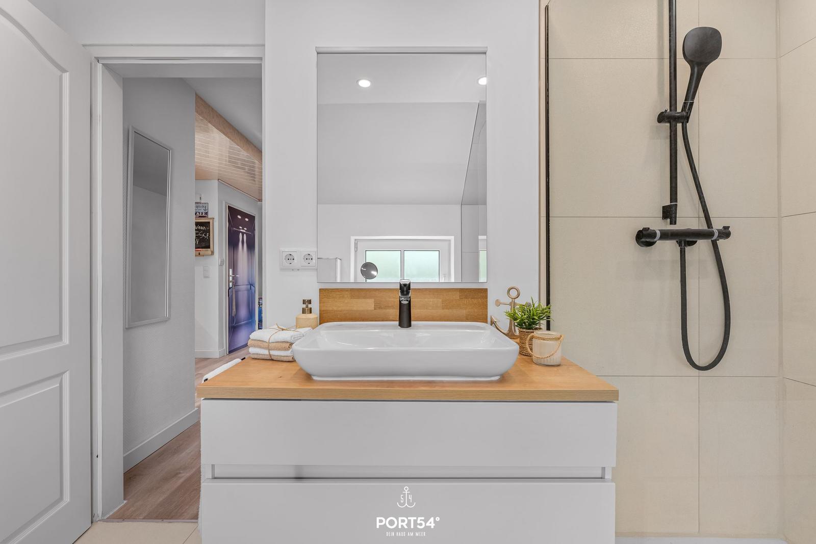 Bad mit Waschbecken, Dusche und Spiegel. Holzoberfläche und moderne Armaturen.