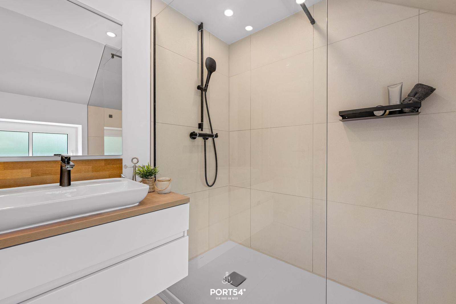 Moderne Dusche mit Glaswand und Waschbecken mit Holzoberfläche.