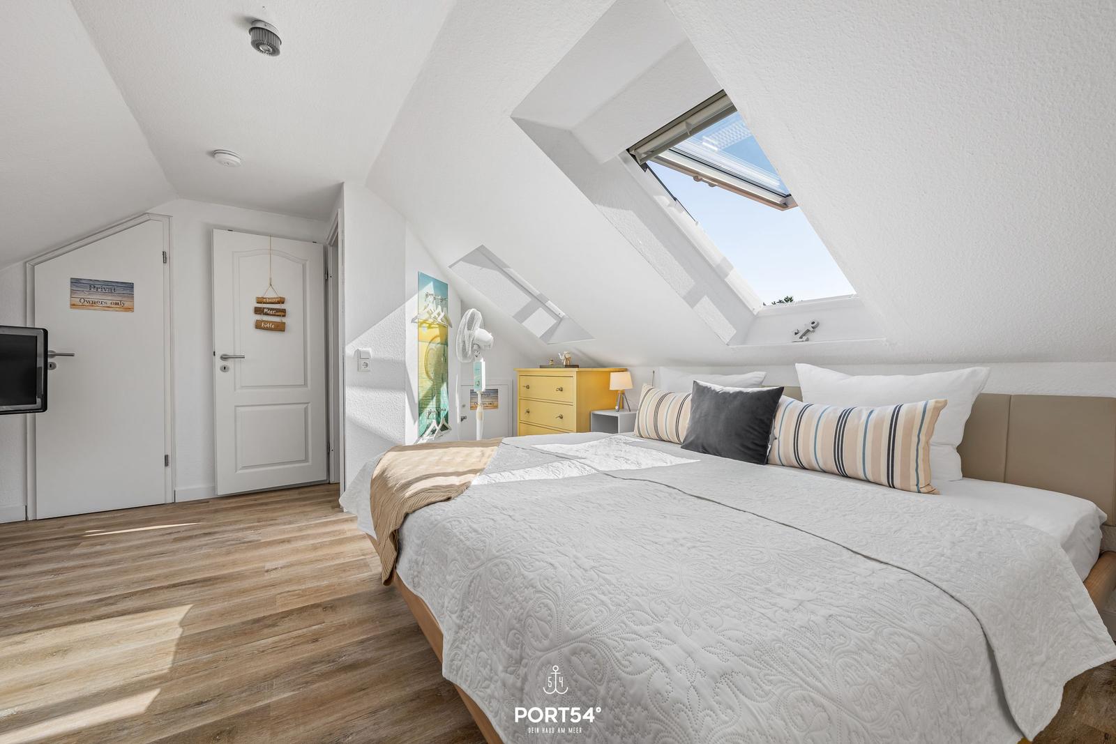 Schlafzimmer mit Dachschrägen, Dachfenster und gelbem Schrank.