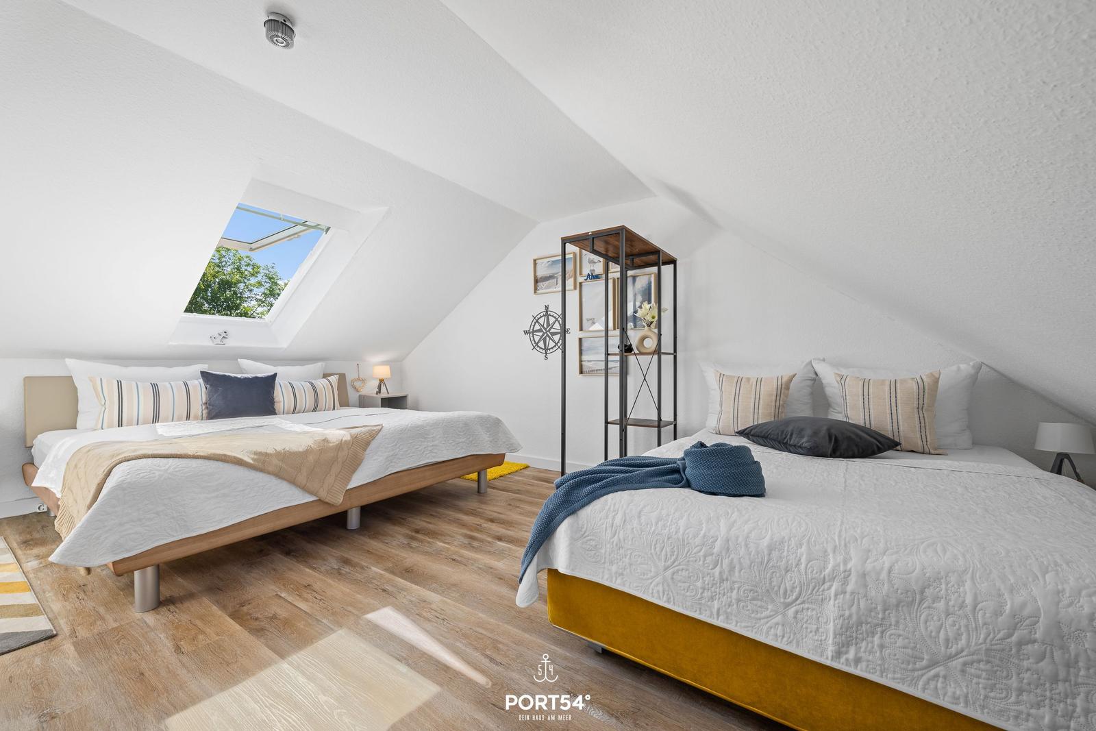 Zwei Betten unter Dachschrägen mit Blick auf den Himmel.