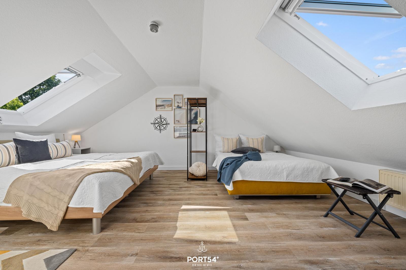 Zwei Betten unter Dachschrägen mit Dachfenstern und Holzboden.