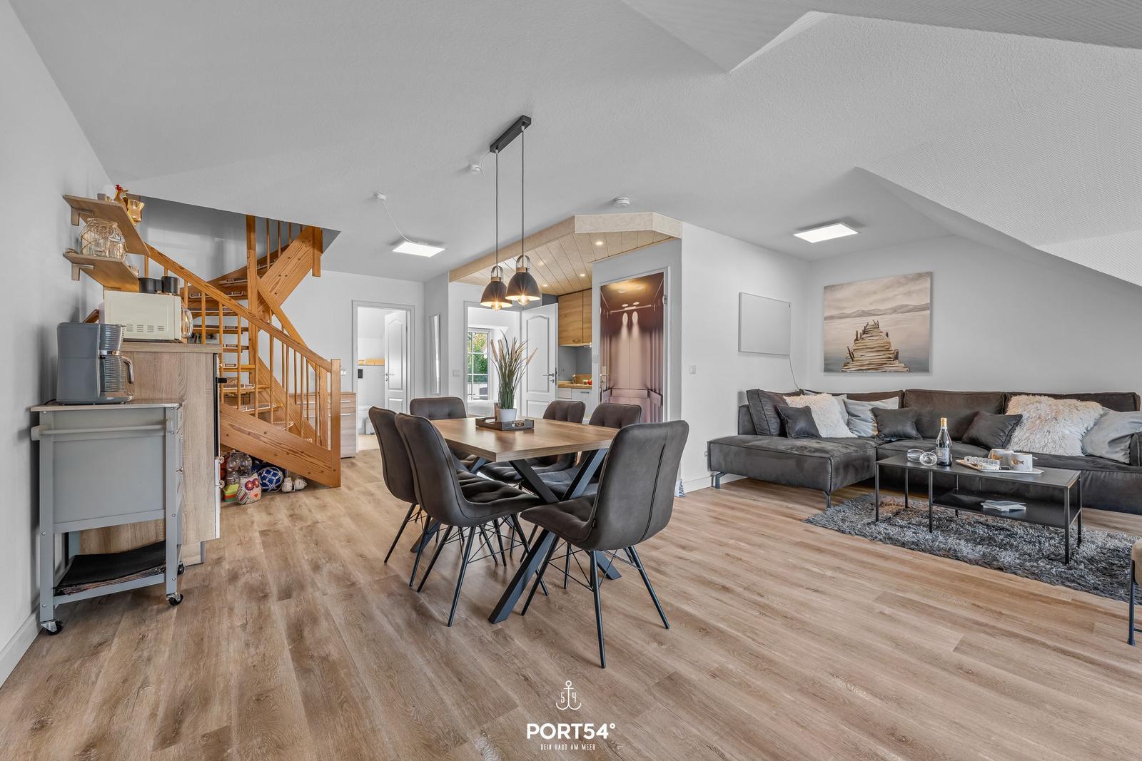 Wohn- und Essbereich mit Holzboden, Sofa und Esstisch.