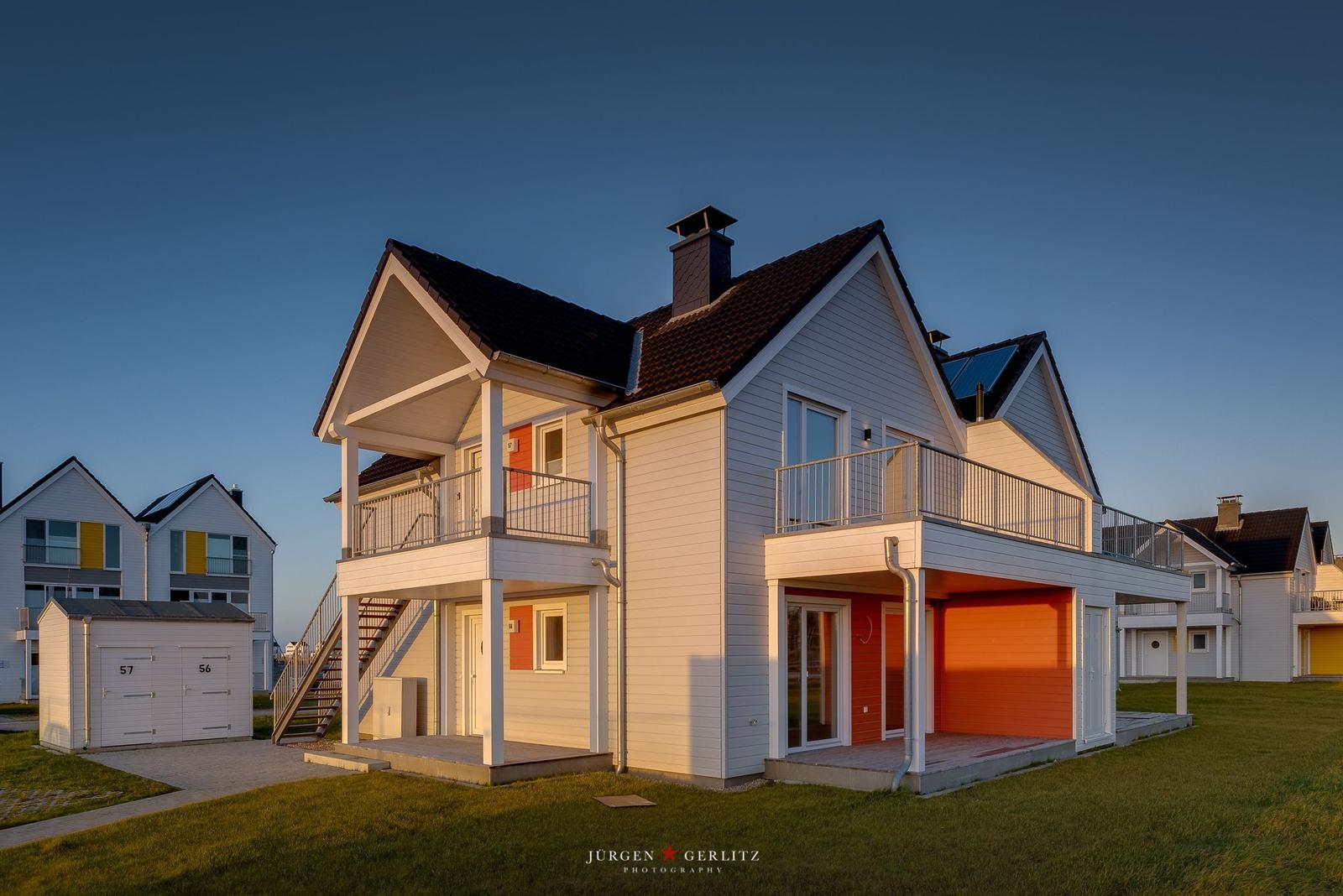 Modernes Ferienhaus mit Balkon und Garage. Außenbereich mit Grünfläche.