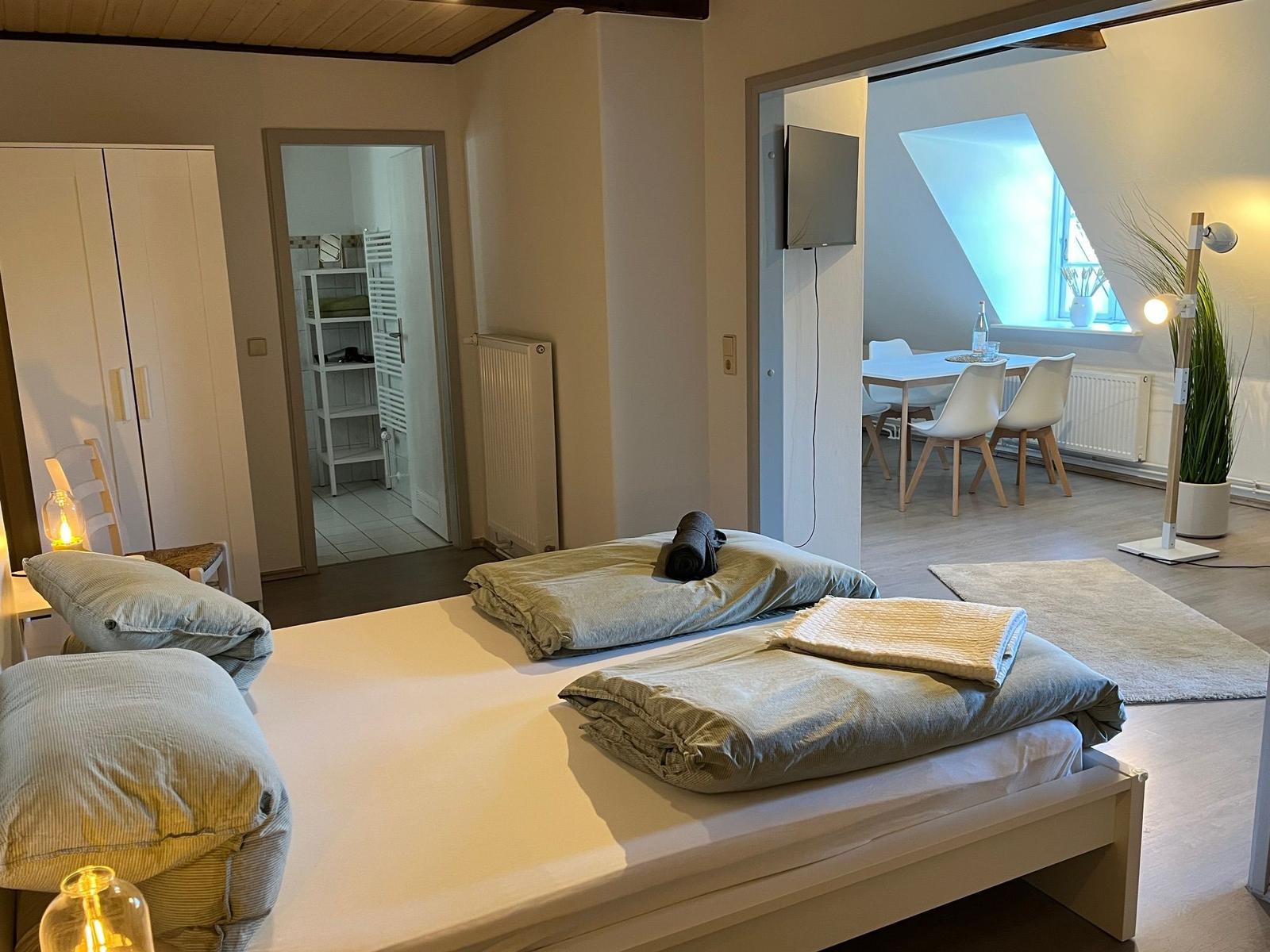 Schlafzimmer mit Doppelbett, angrenzender Küche und Bad.