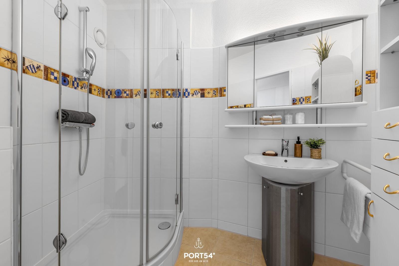 Badezimmer mit Dusche, Waschbecken und Spiegelschrank.