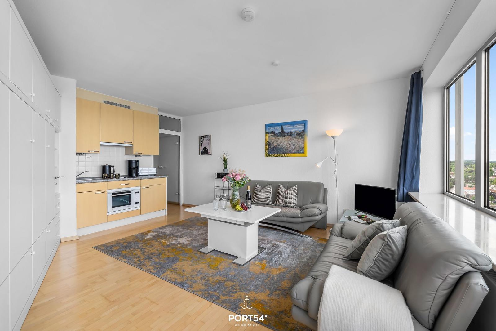 Wohnküche mit Sofa, Tisch und Blick aus Fenster.