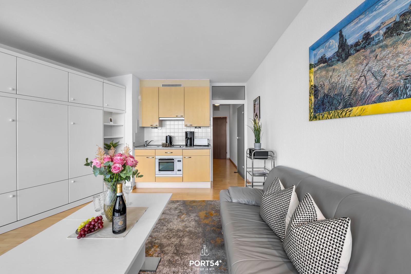 Wohn- und Küchenbereich mit Sofa, Tisch und Wandbild.