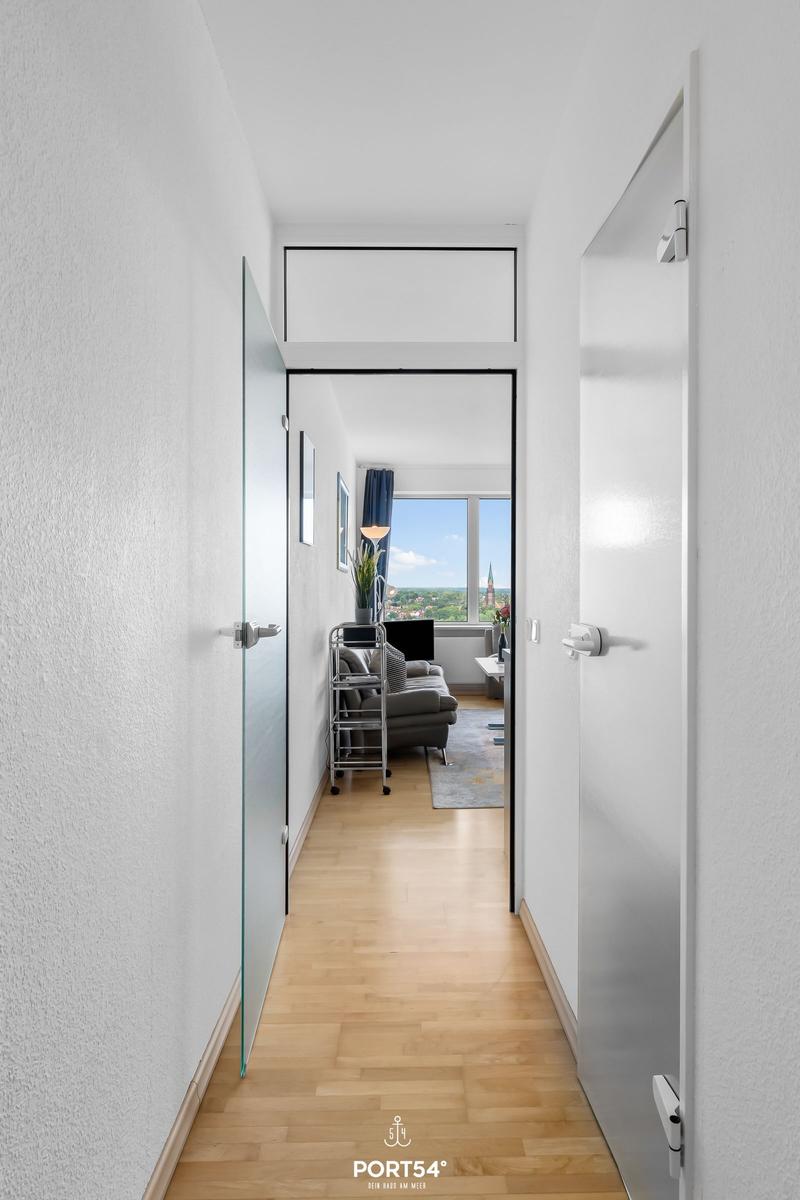 Flur mit Holzboden führt in Wohnzimmer mit Blick auf Stadt.