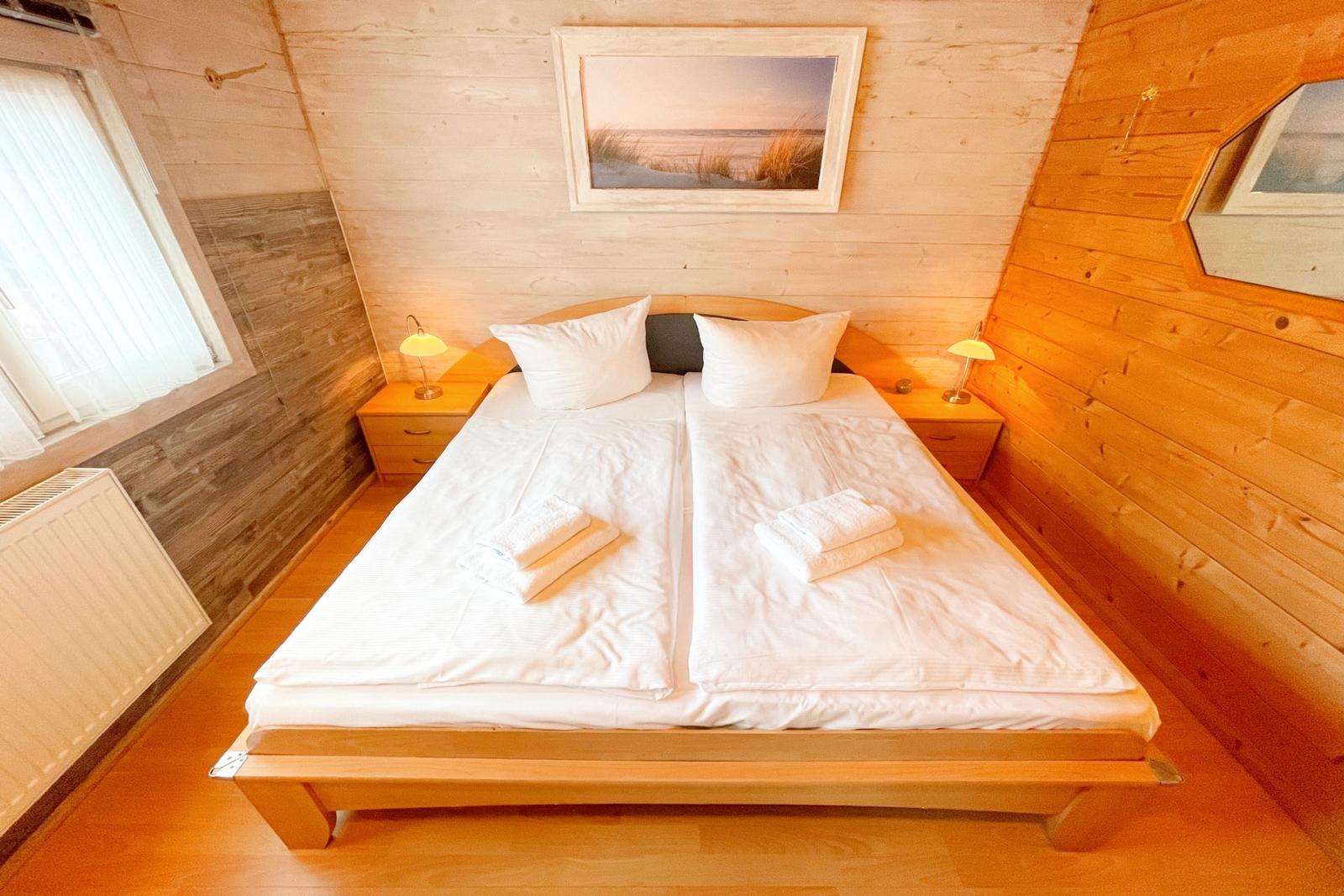Schlafzimmer mit Holzwand, Bett und Nachttischen