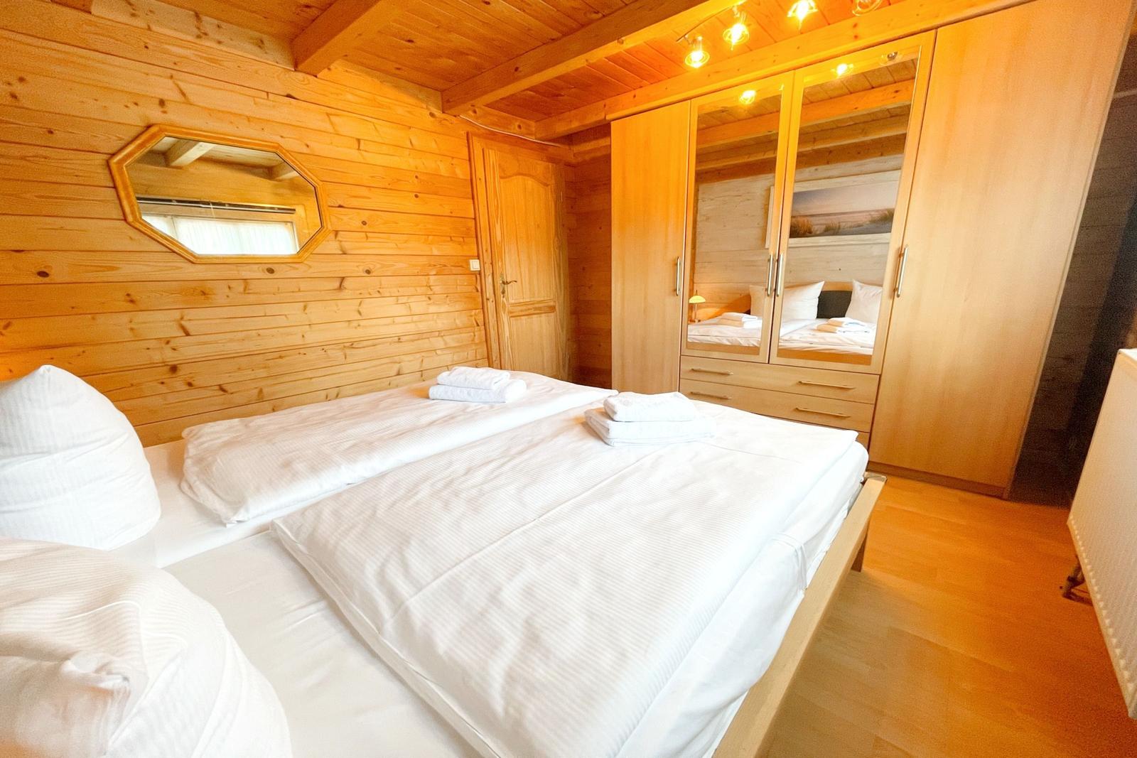 Schlafzimmer mit Holzwand, Bett und Kleiderschrank