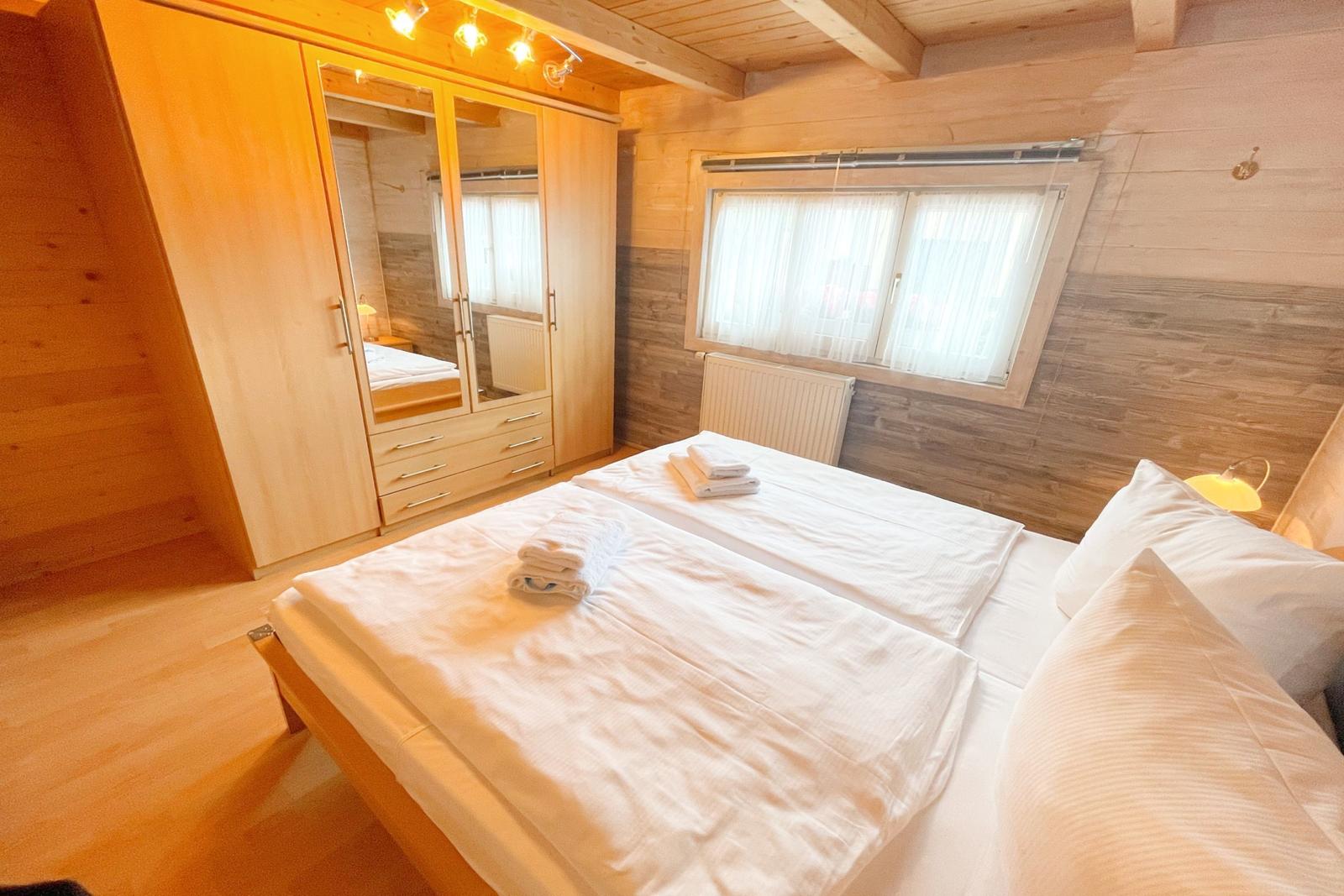 Schlafzimmer mit Bett, Kleiderschrank und Fenster