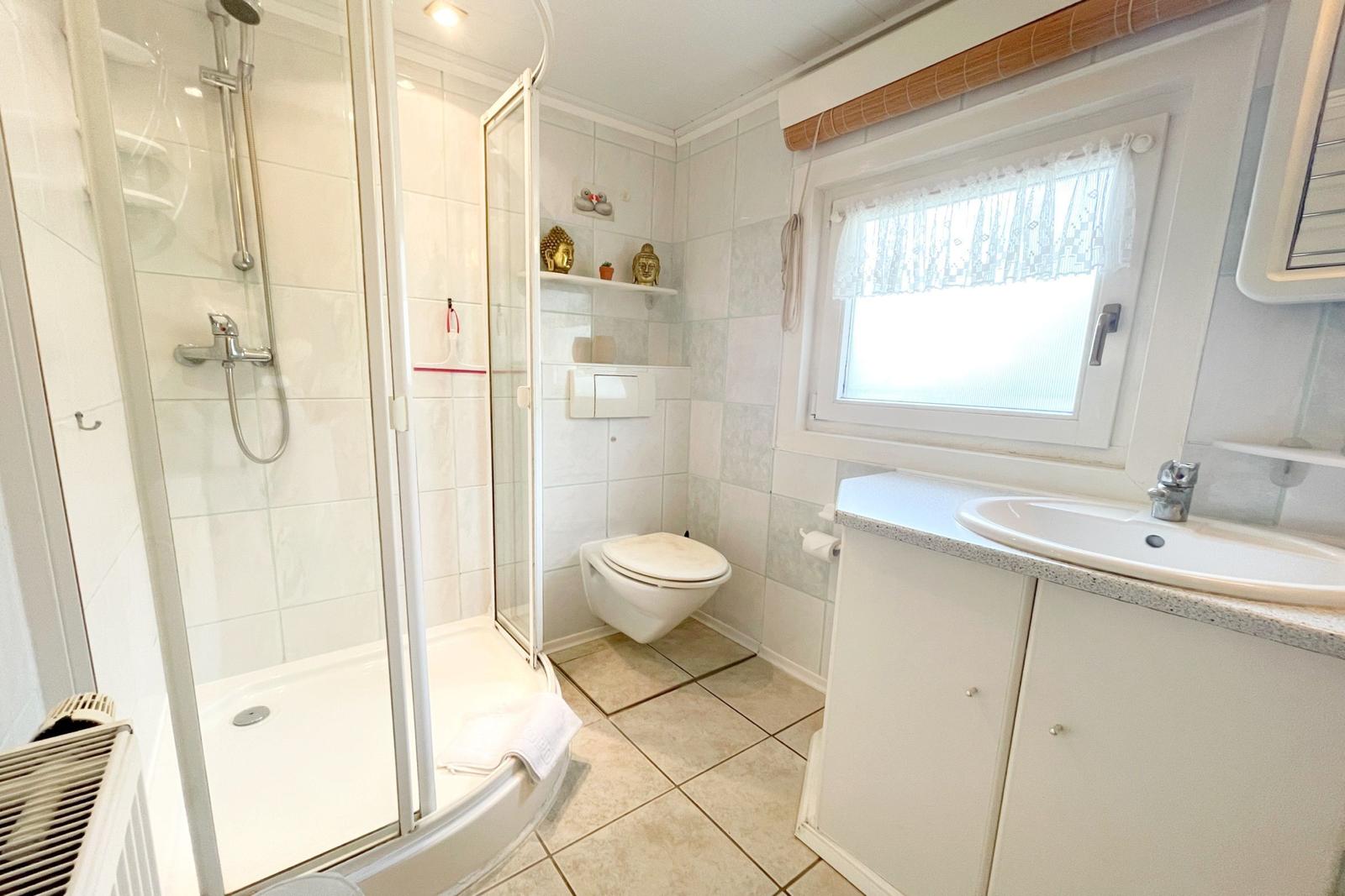 Badezimmer mit Dusche, Toilette und Waschbecken.