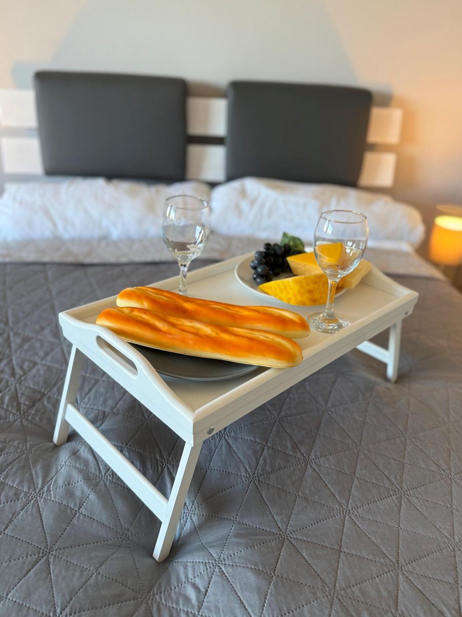 Ein Bett mit einem Tablett, auf dem Brot, Käse, Trauben und zwei Gläser stehen.