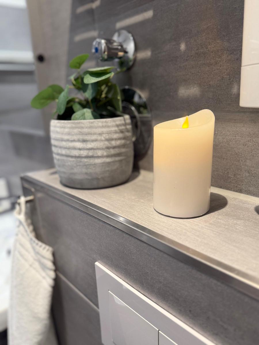 Badezimmer mit Pflanze, LED-Streichhölzer und modernem Waschbecken.