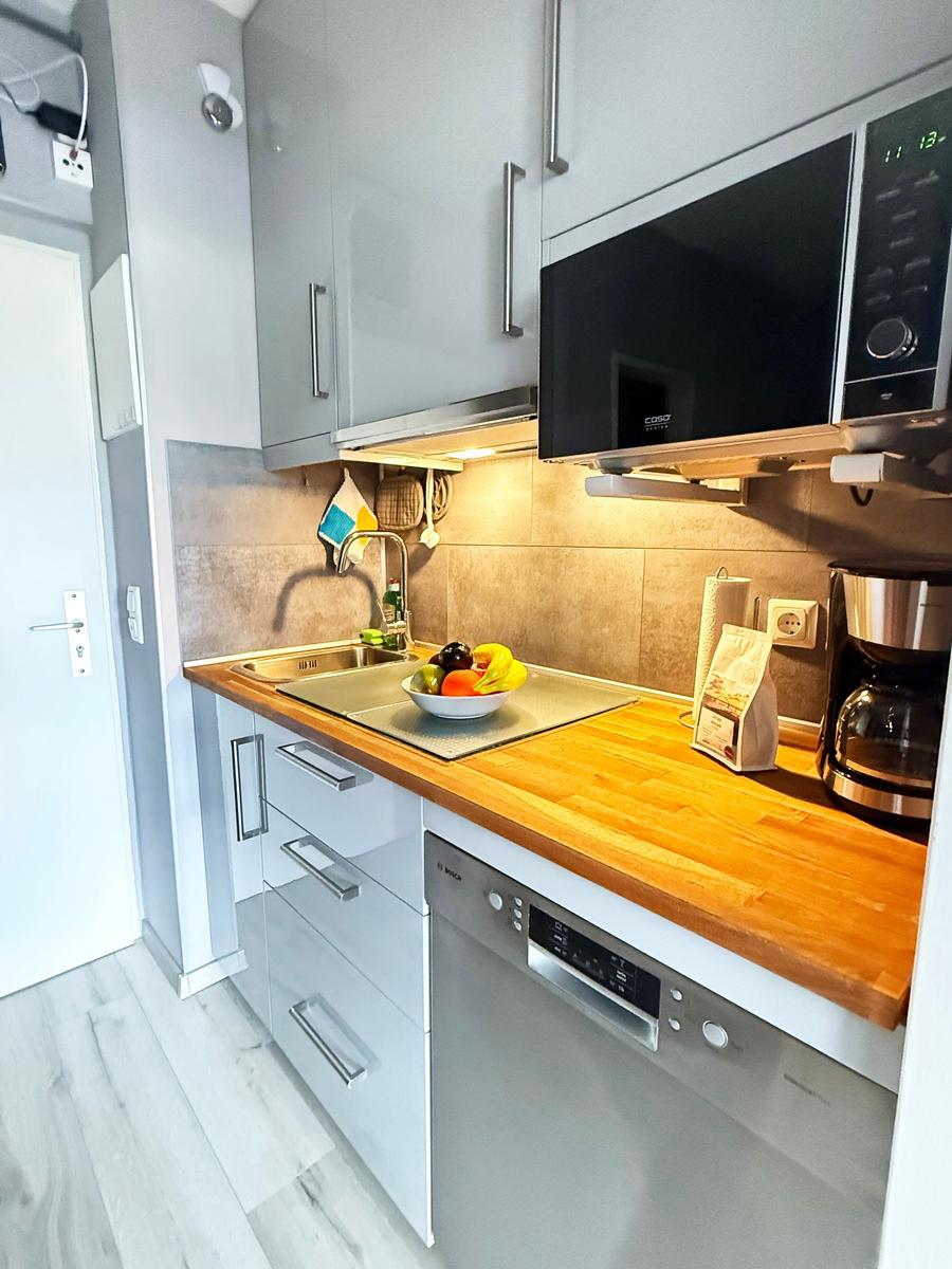 Küche mit Holzplatte, Spüle, Mikrowelle und Kaffeemaschine.