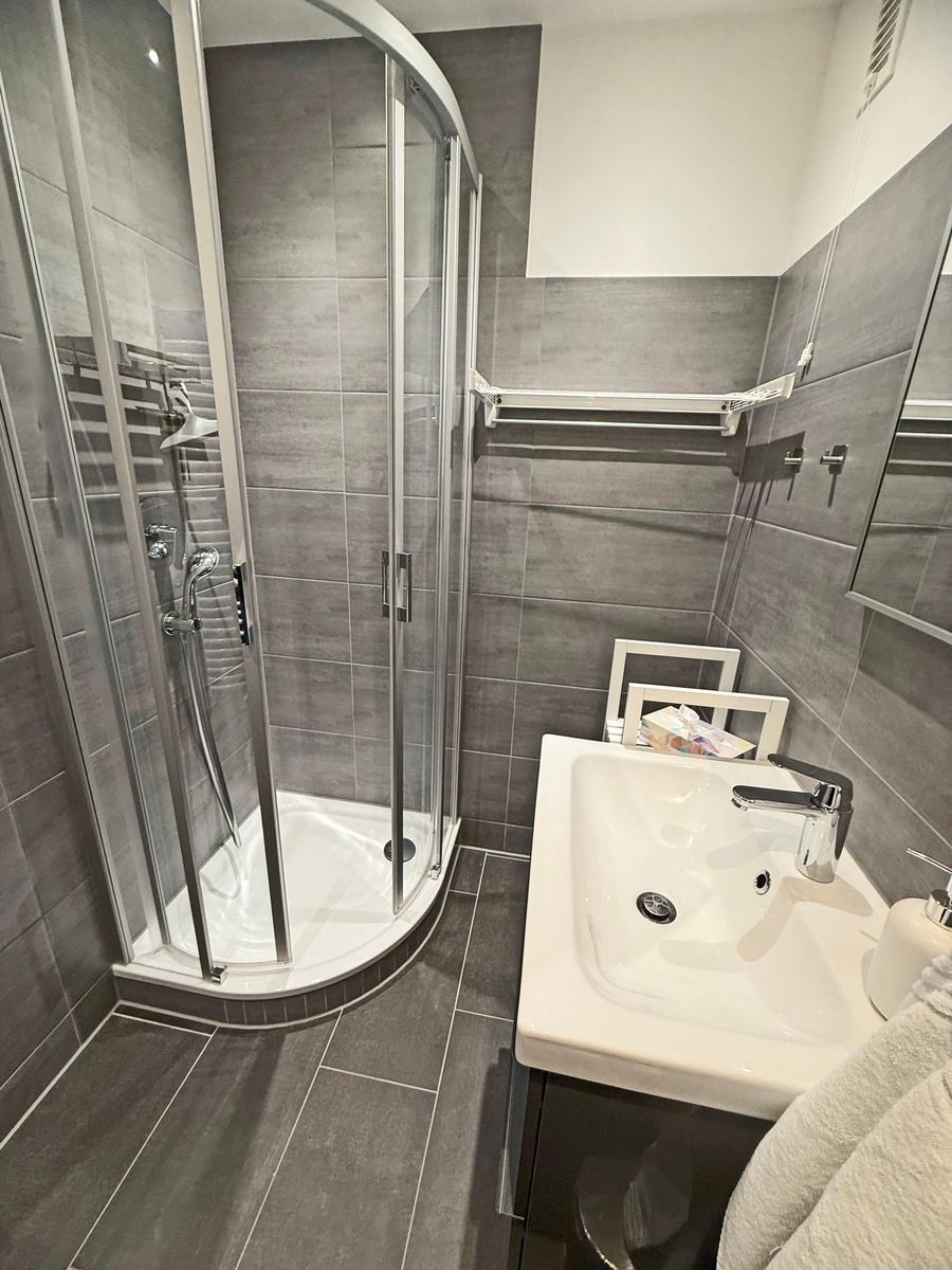 Badezimmer mit Dusche, Waschbecken und Spiegelschrank.