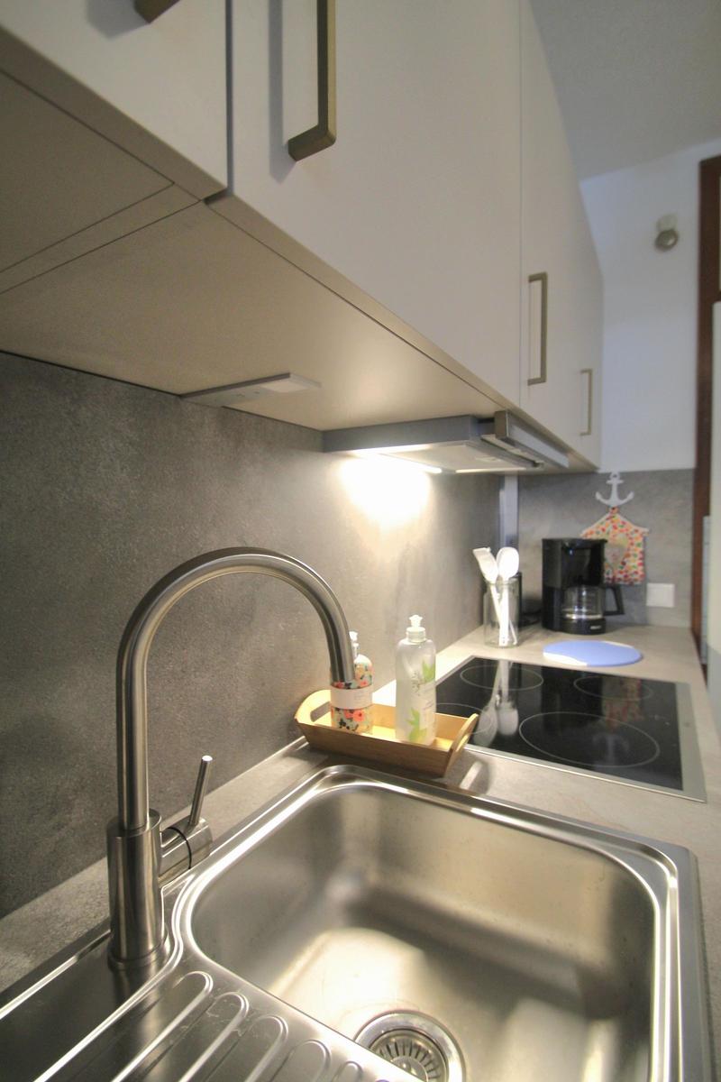 Küche mit Edelstahlspüle, Induktionskochfeld und Küchenarmatur.