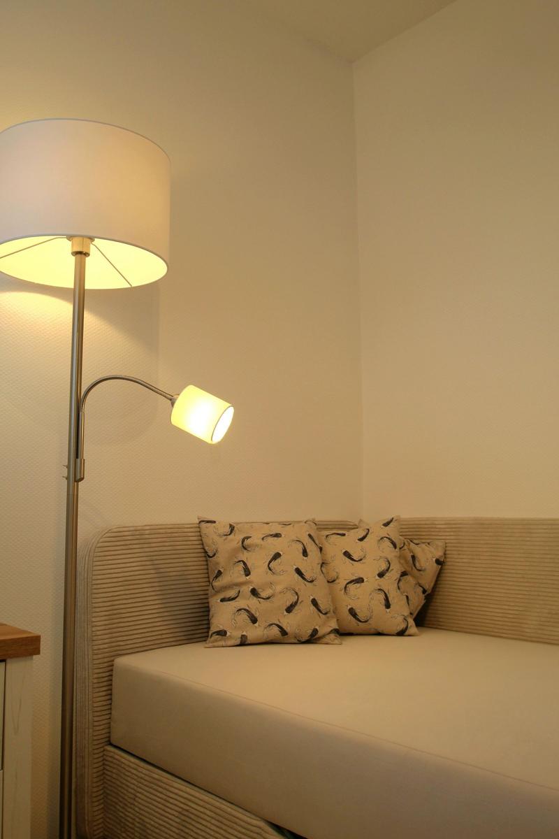 Beleuchtete Ecke mit Sofa und Stehlampe.