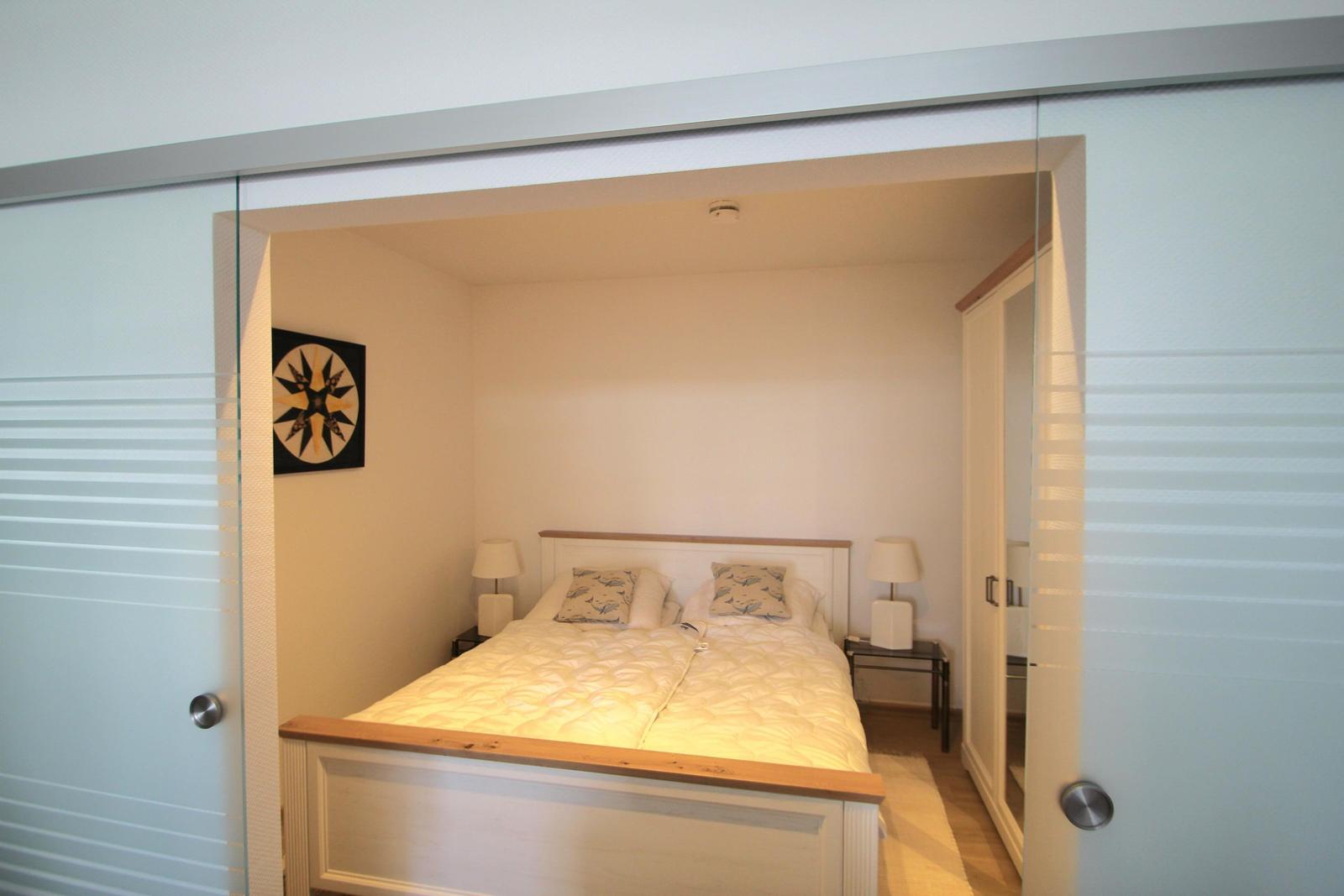 Schlafzimmer mit Doppelbett, Nachttischen und Wandbild.