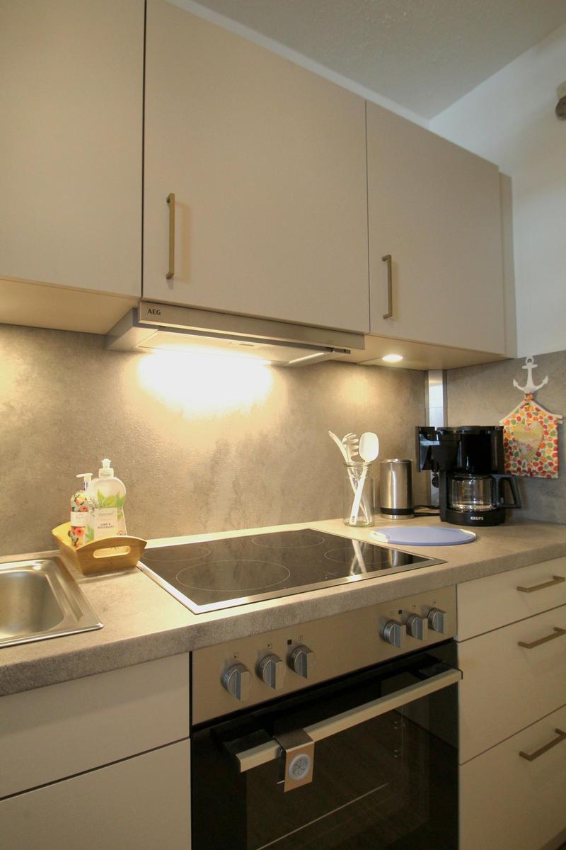 Küche mit Induktionskochfeld, Dunstabzug und Kaffeemaschine.