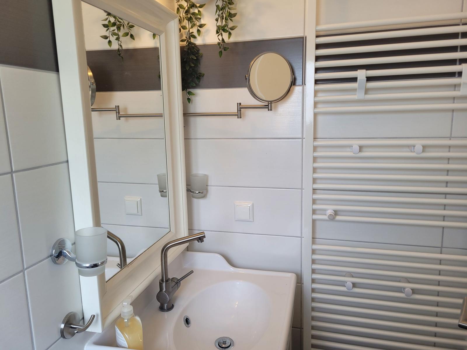 Bad mit Waschbecken, Spiegel und Heizkörper