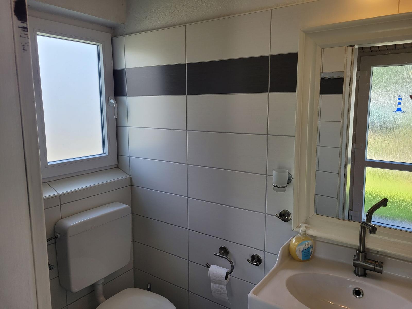 Badezimmer mit Toilette, Waschbecken und Fenster.