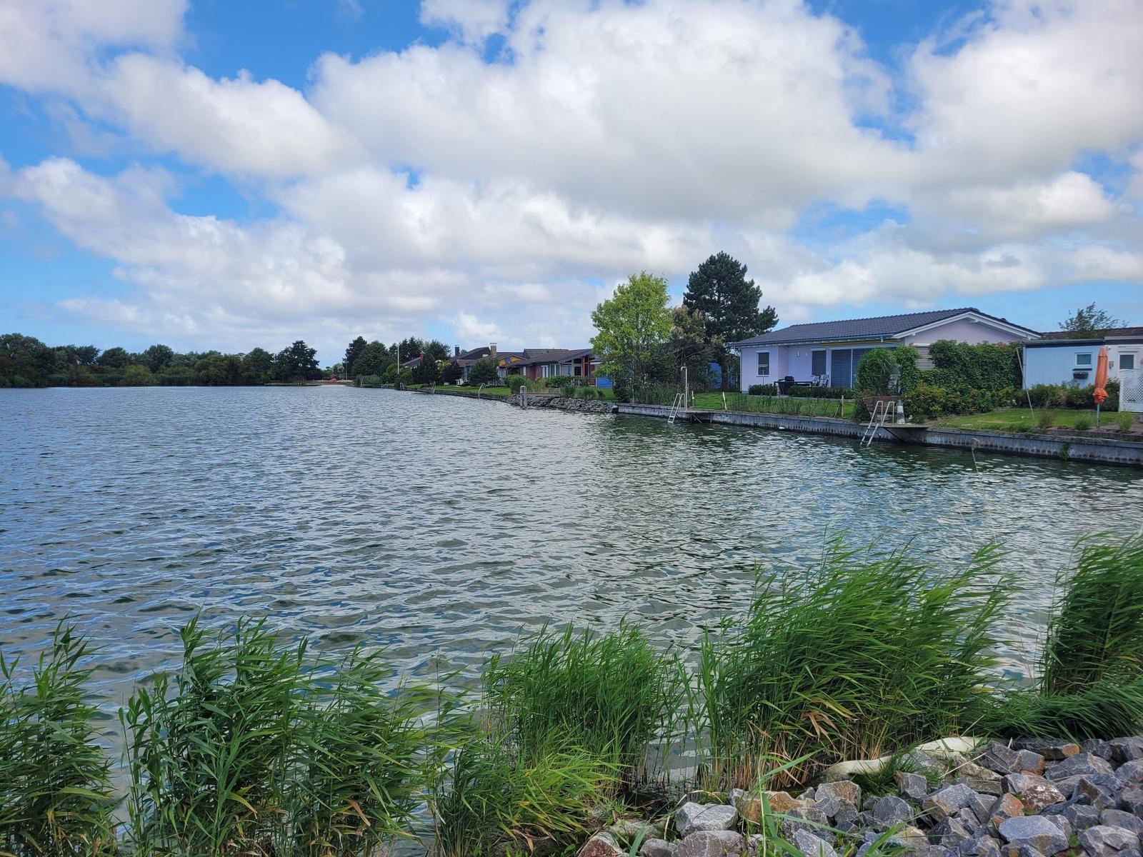 Häuser am Wasser mit Bootsstegen und Grünflächen.