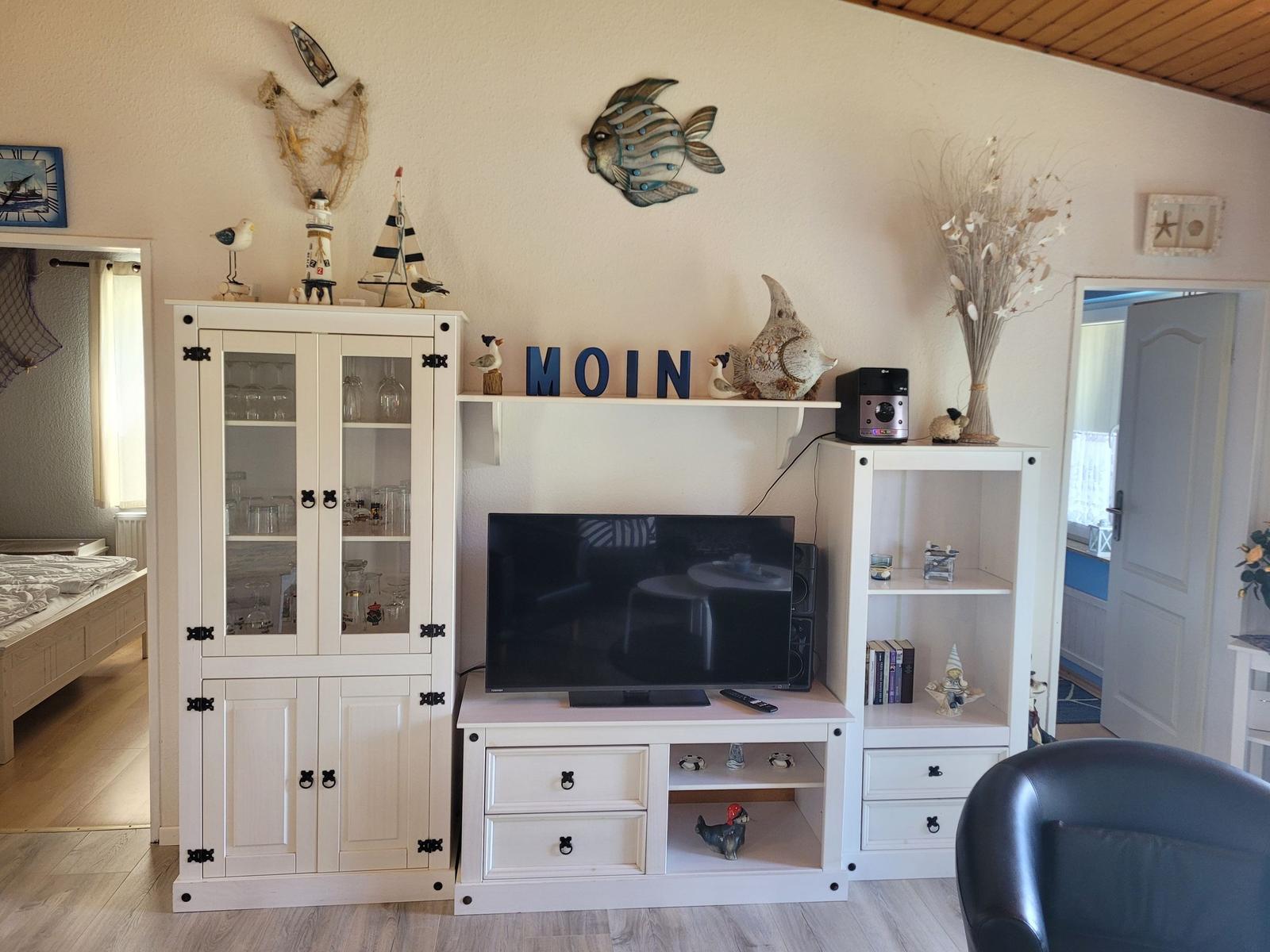 Wohnzimmer mit TV, Schrank und Dekoration.