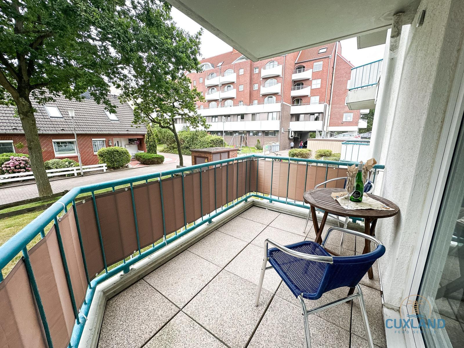 Terrasse mit Tisch, Stühlen und Blick auf Wohnhaus und Grünflächen