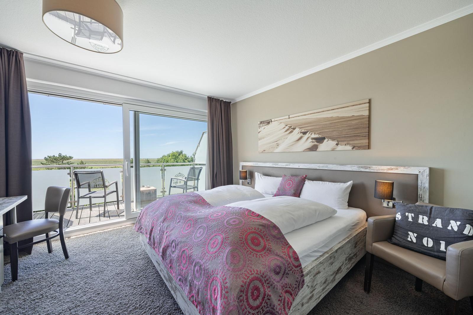 Schlafzimmer mit Balkon und Bett mit Musterdecke.