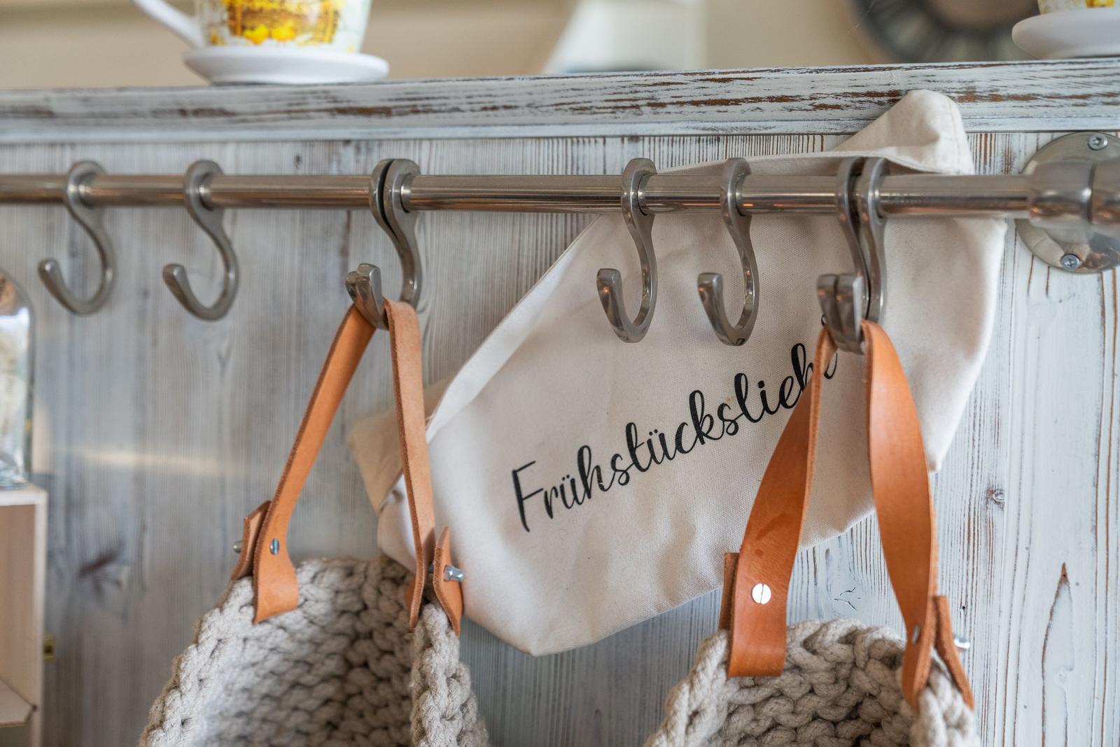 Haken an einer Holzwand mit Taschen und einem Stoffbeutel.