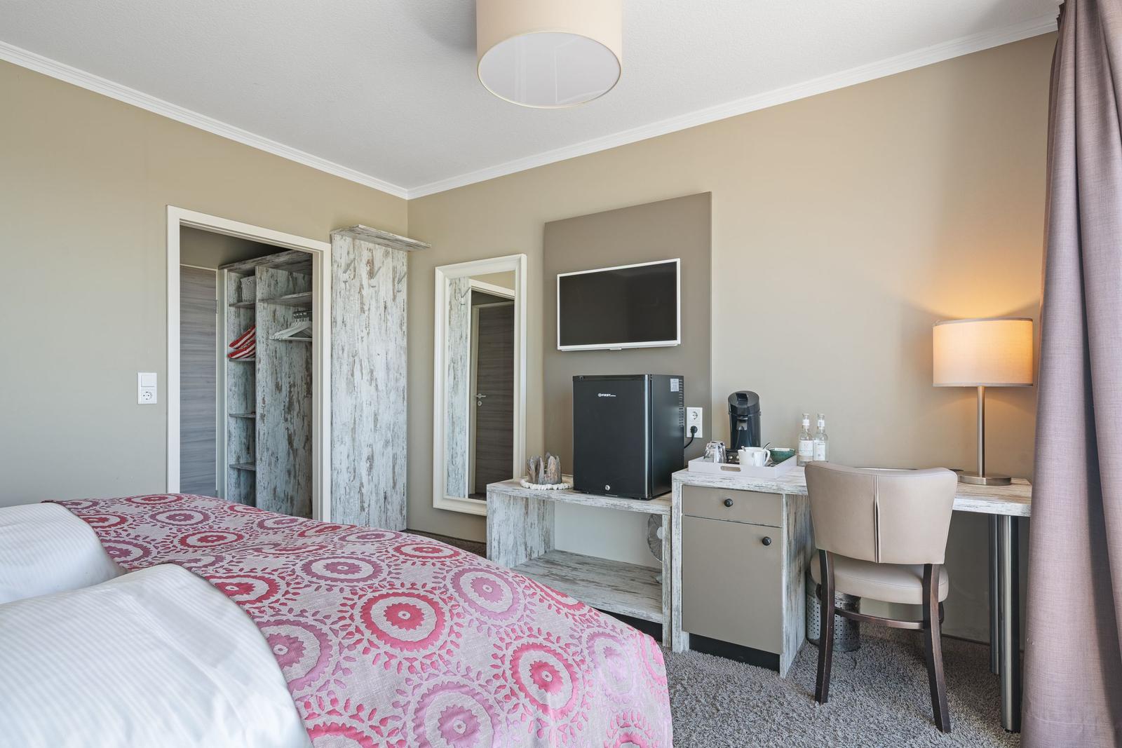 Schlafzimmer mit Bett, Schreibtisch, Fernseher und Kleiderschrank.