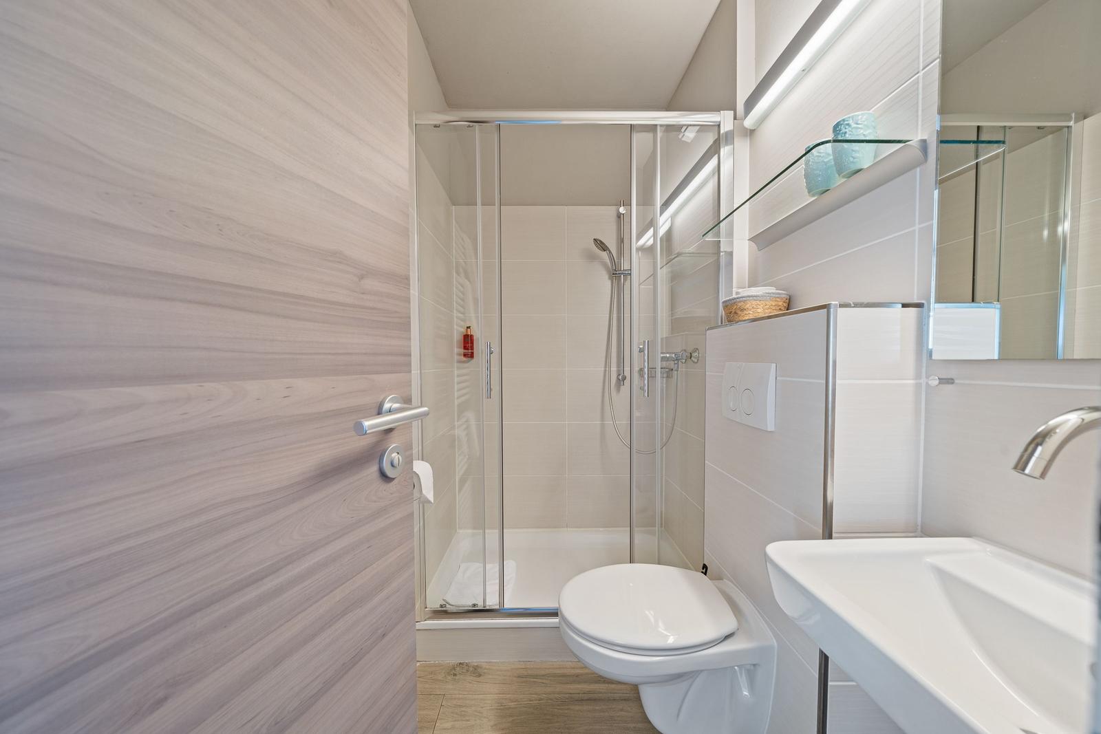 Badezimmer mit Dusche, Toilette und Waschbecken.