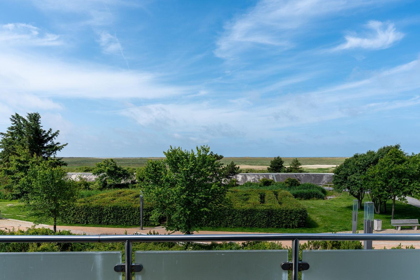 Blick von Balkon auf grüne Flächen und Himmel