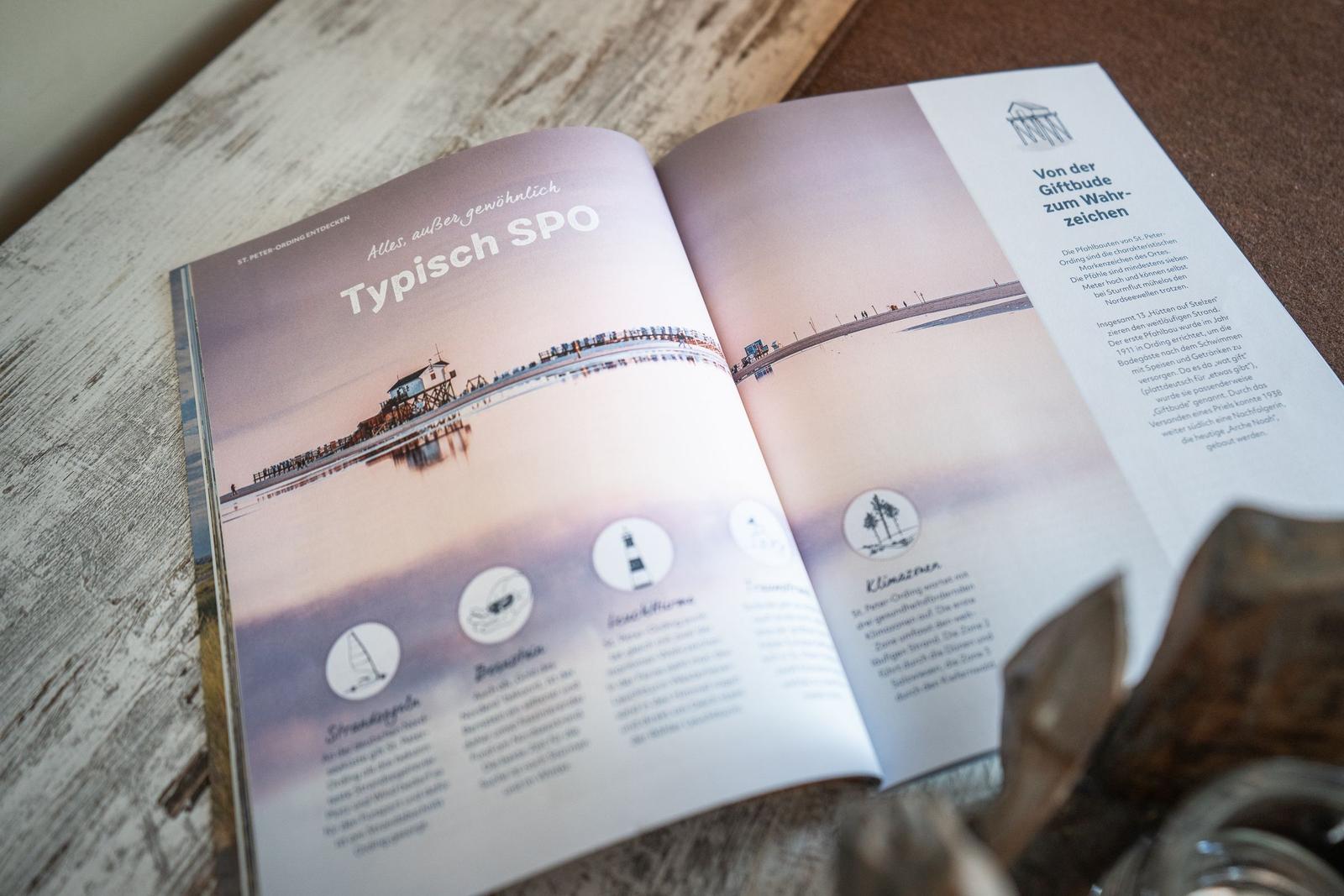 Offener Buchseitenblick auf St. Peter-Ording mit Pfahlbauten und Strandinformationen.