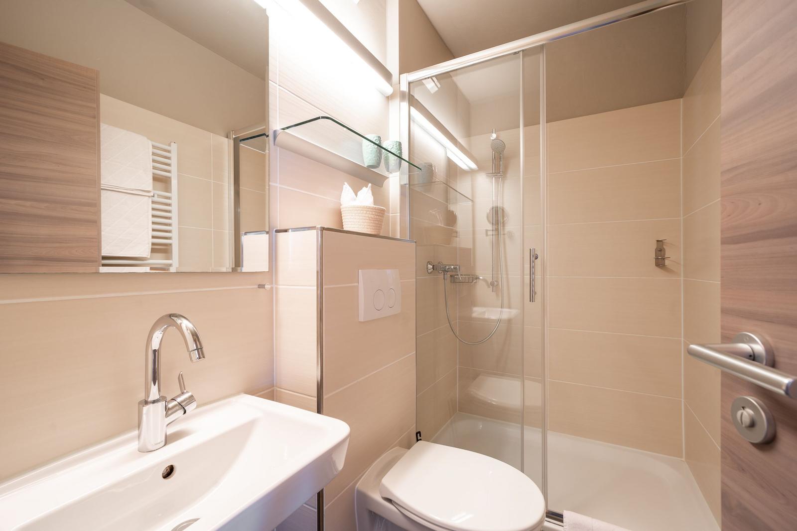 Badezimmer mit Dusche, Waschbecken und Toilette.