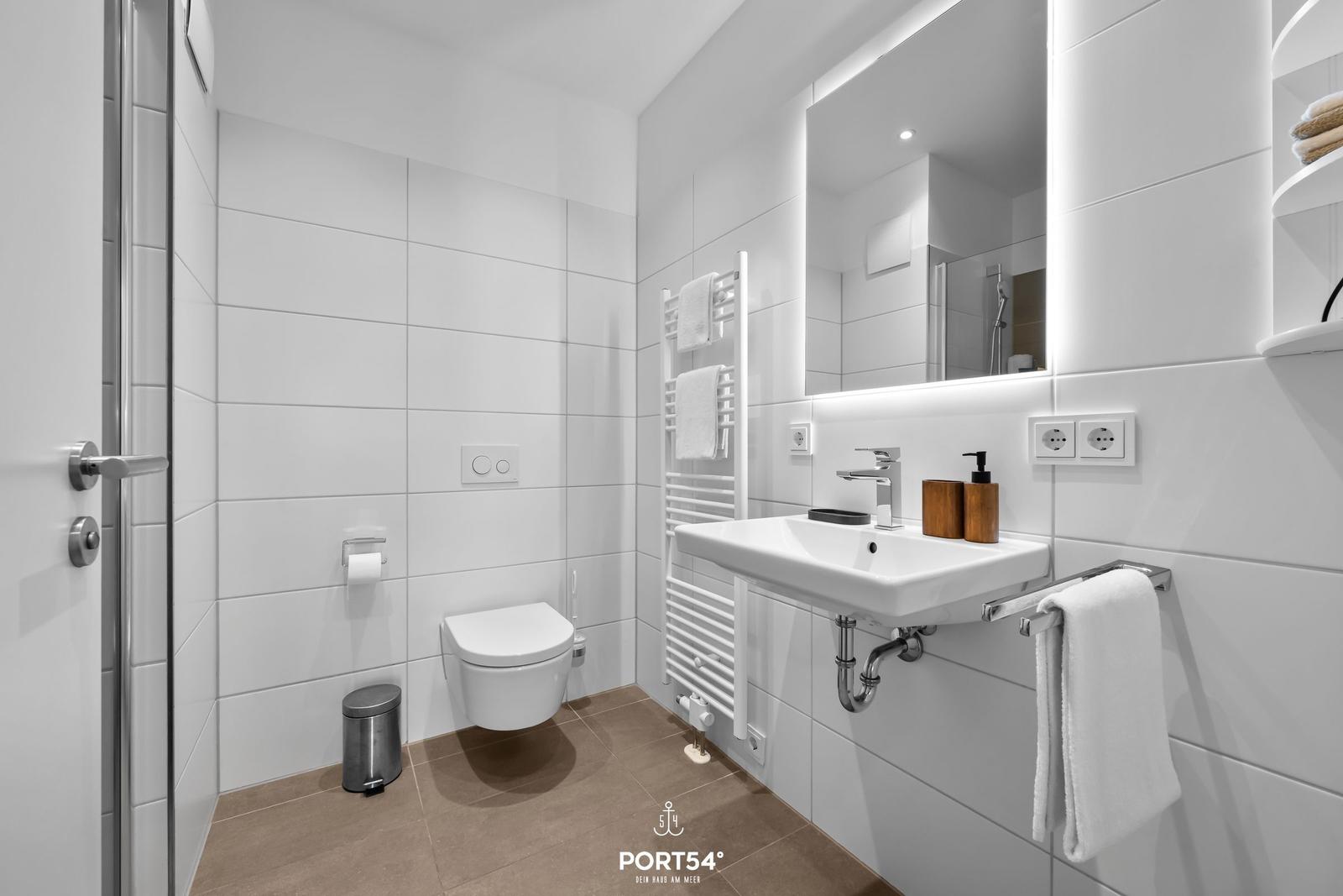 Badezimmer mit Toilette, Waschbecken und Spiegel