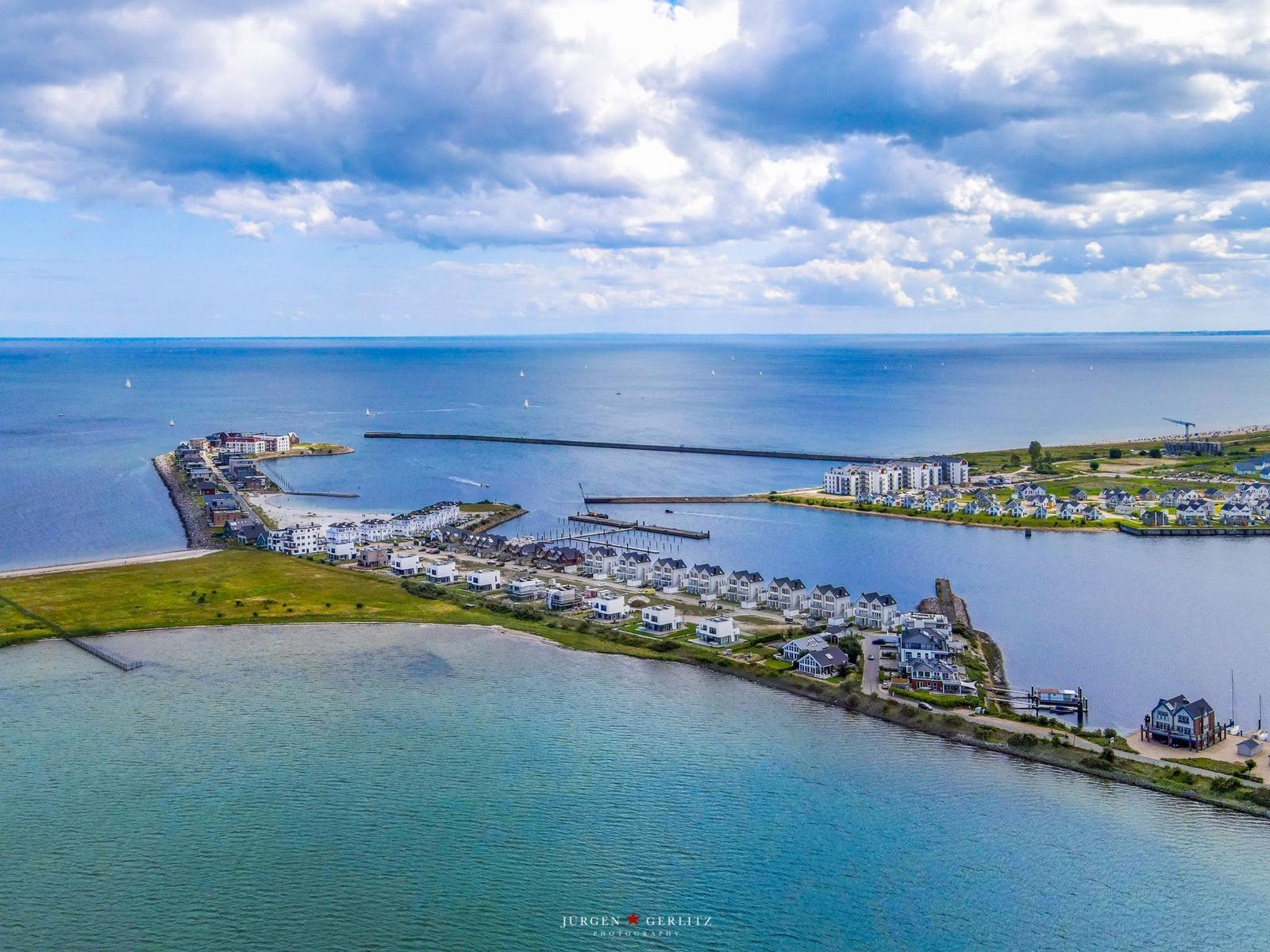 Aerial view of a coastal town with houses, docks, and sailboats on the water.