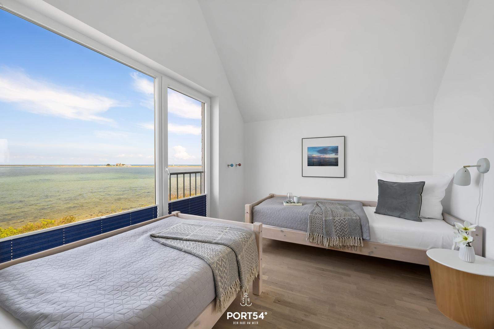 Zwei Betten mit Blick aufs Wasser und Balkon. Wandbild und Nachttisch.