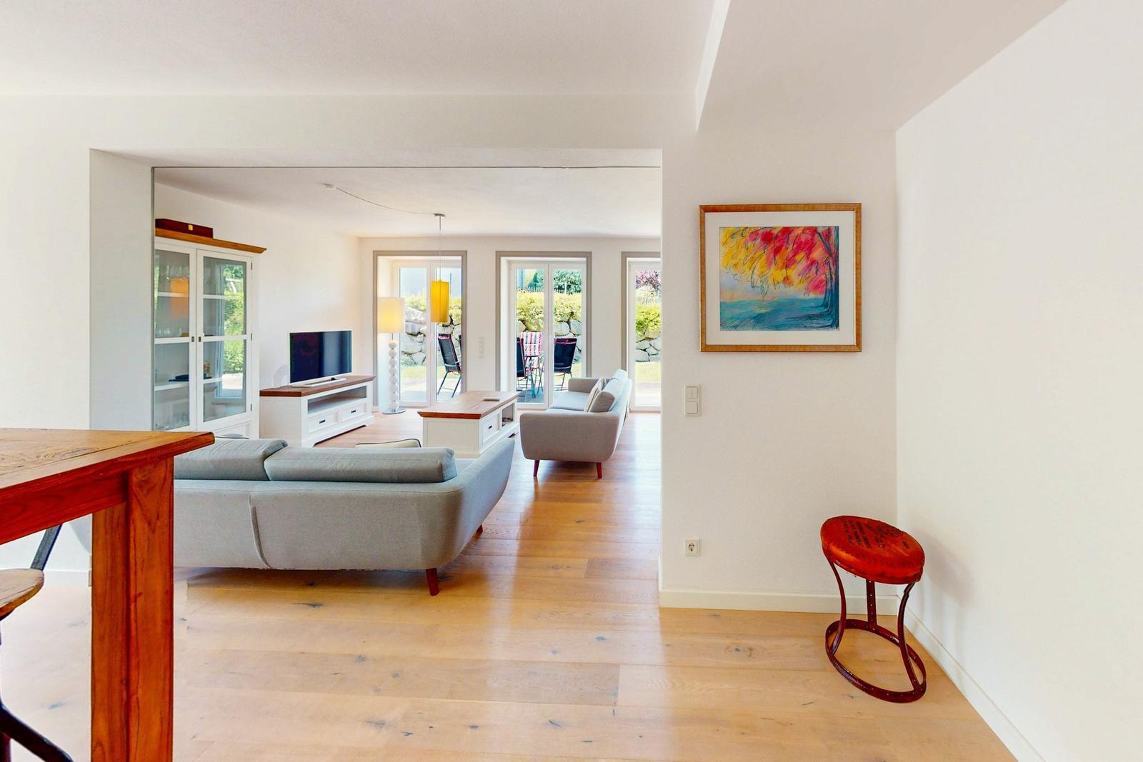 Wohnbereich mit Sofa, Fernseher und Blick auf die Terrasse.